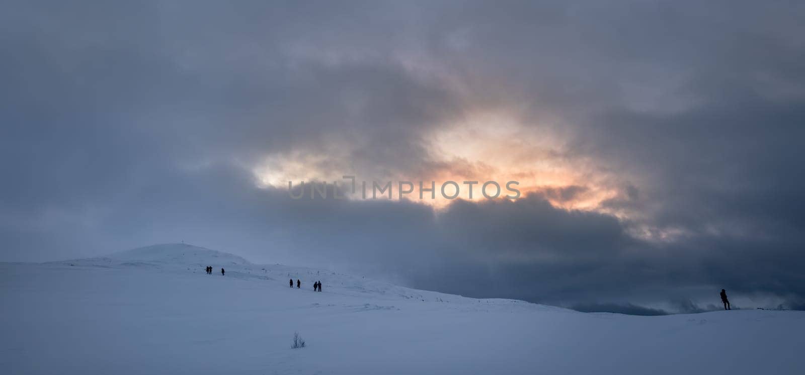 Unidentifiable people walking towards Storsteinen mountain summit and peak in the snow among the wonderful winter scenery, Norway