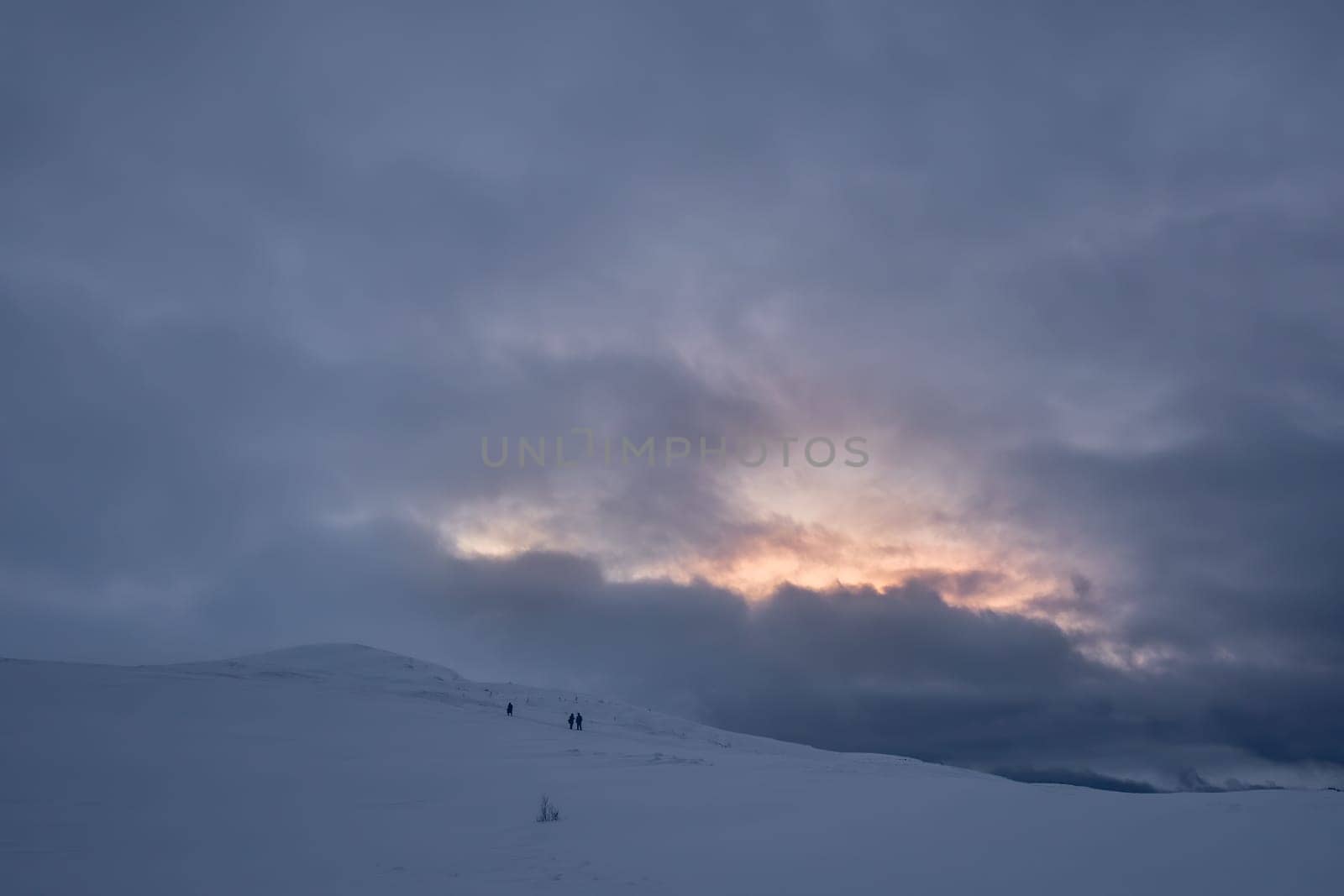 Unidentifiable people walking towards Storsteinen mountain summit and peak in the snow among the wonderful winter scenery, Norway