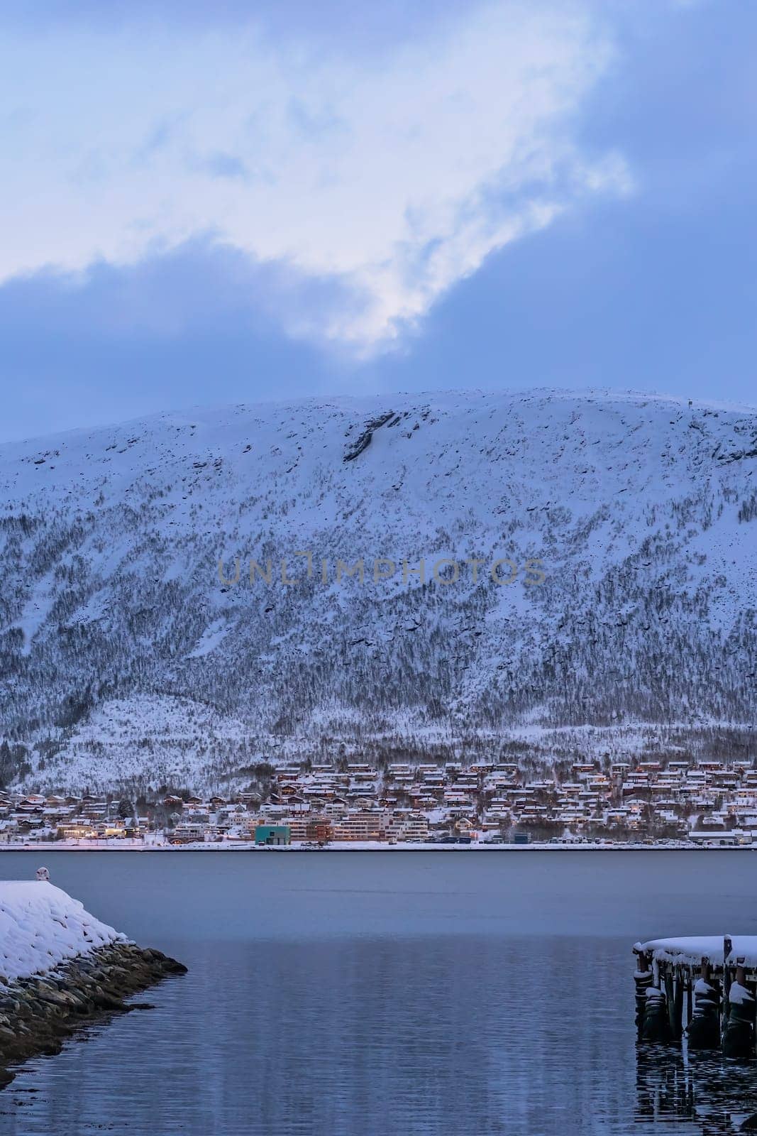 Residential hillside houses in Tromso suburb covered in a deep snow at dusk, Norway