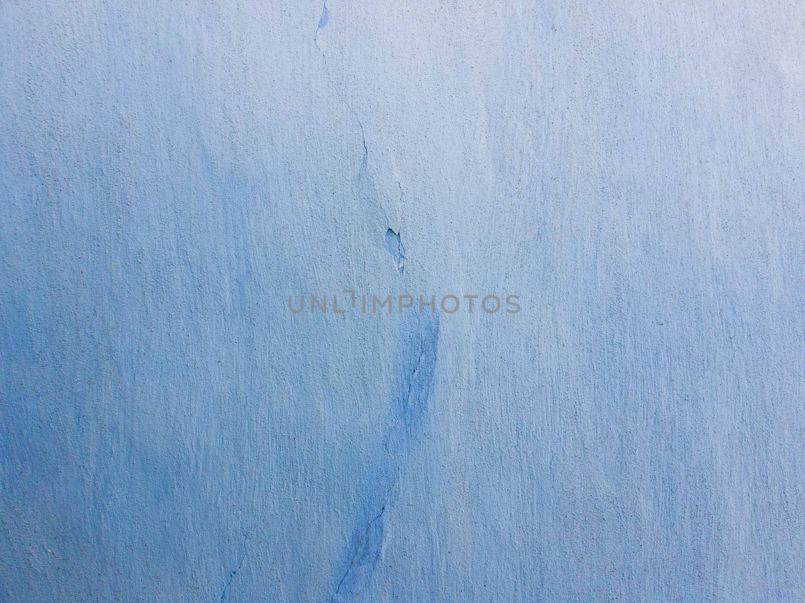 Blue lime coating texture on the old wall texture with a crack in the middle. Abstract rustic grunge plaster, stucco retro style.