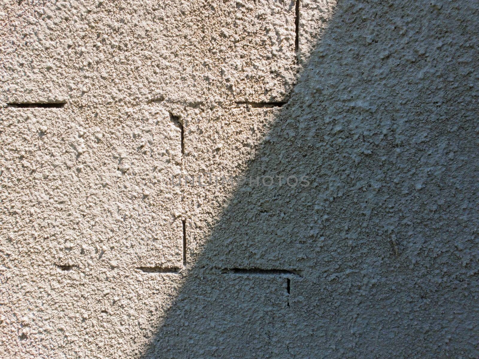 Old grey stone masonry wall texture made of foam blocks or airblocks split on two sides light and shadow. Abstract plastered surface. Grunge, weathered construction structure.