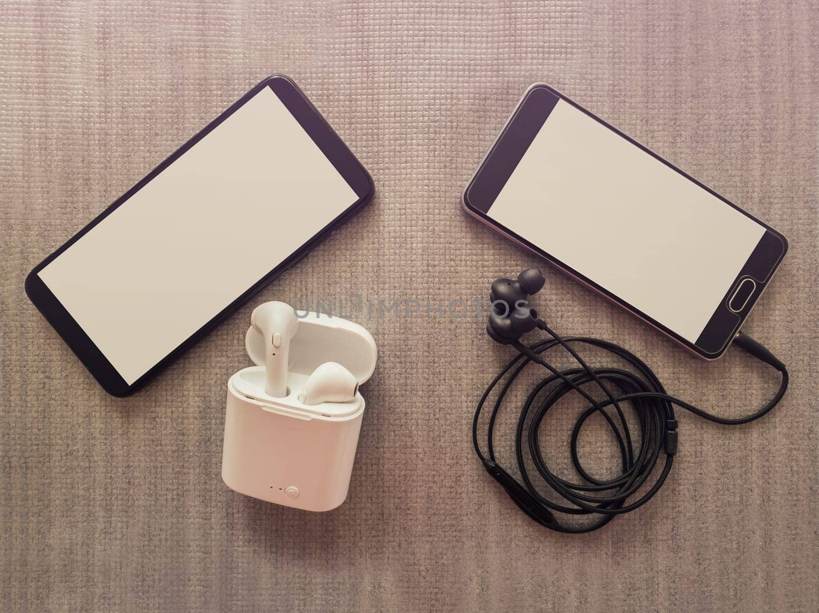 Comparison between two phones, one has 3.5mm jack wired headphones vs wireless earphones for music listening. Pros and cons, opposite contrary. Technology development tendencies, entertainment concept