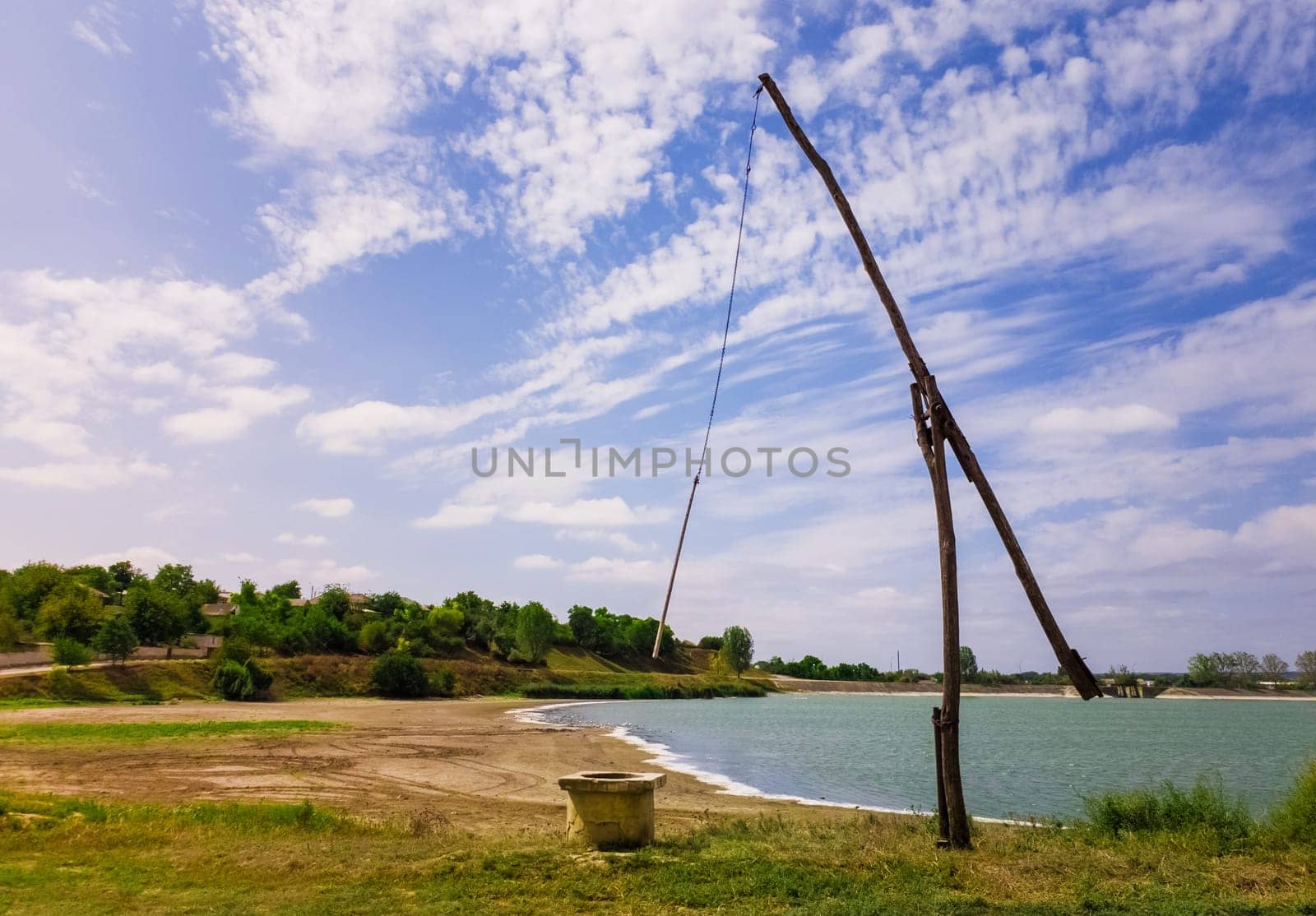 Idyllic countryside scene with an old water well sweep (shadoof) near the Delia lake (Moldova). Also called a counterpoise lift or well pole, is an ancient irrigation tool and used for watering crops.