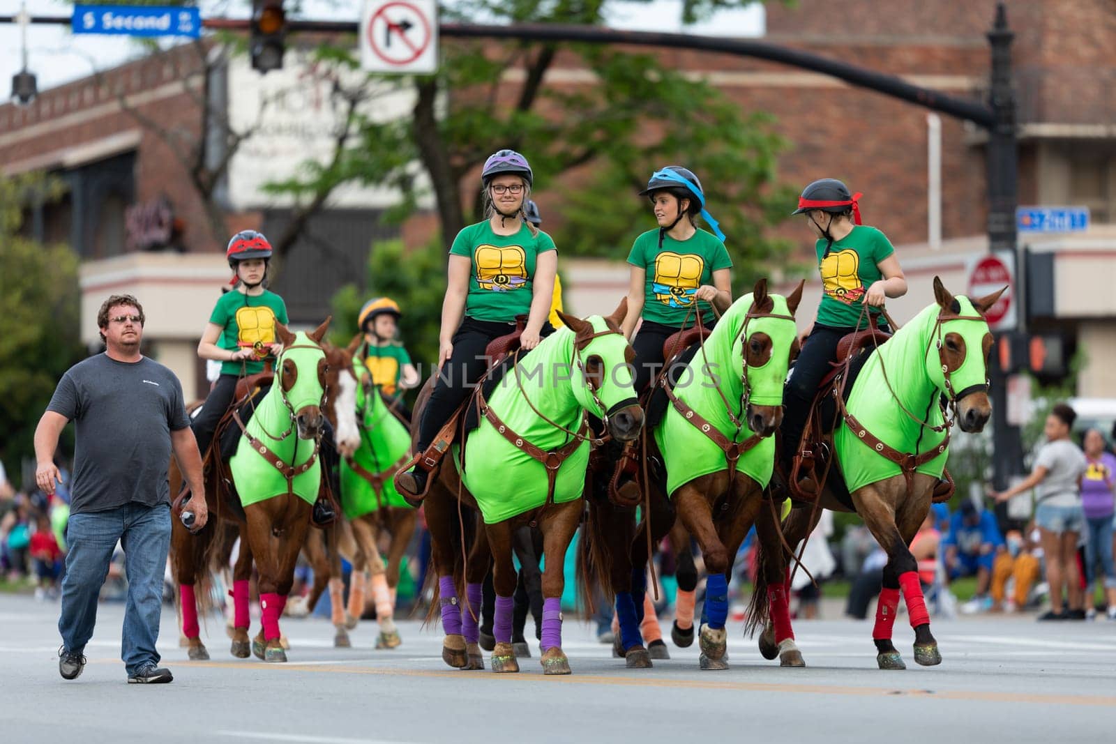 Louisville, Kentucky, USA - May 2, 2019: The Pegasus Parade, young women riding horses, dress up as ninja turtles cartoon characters during the parade
