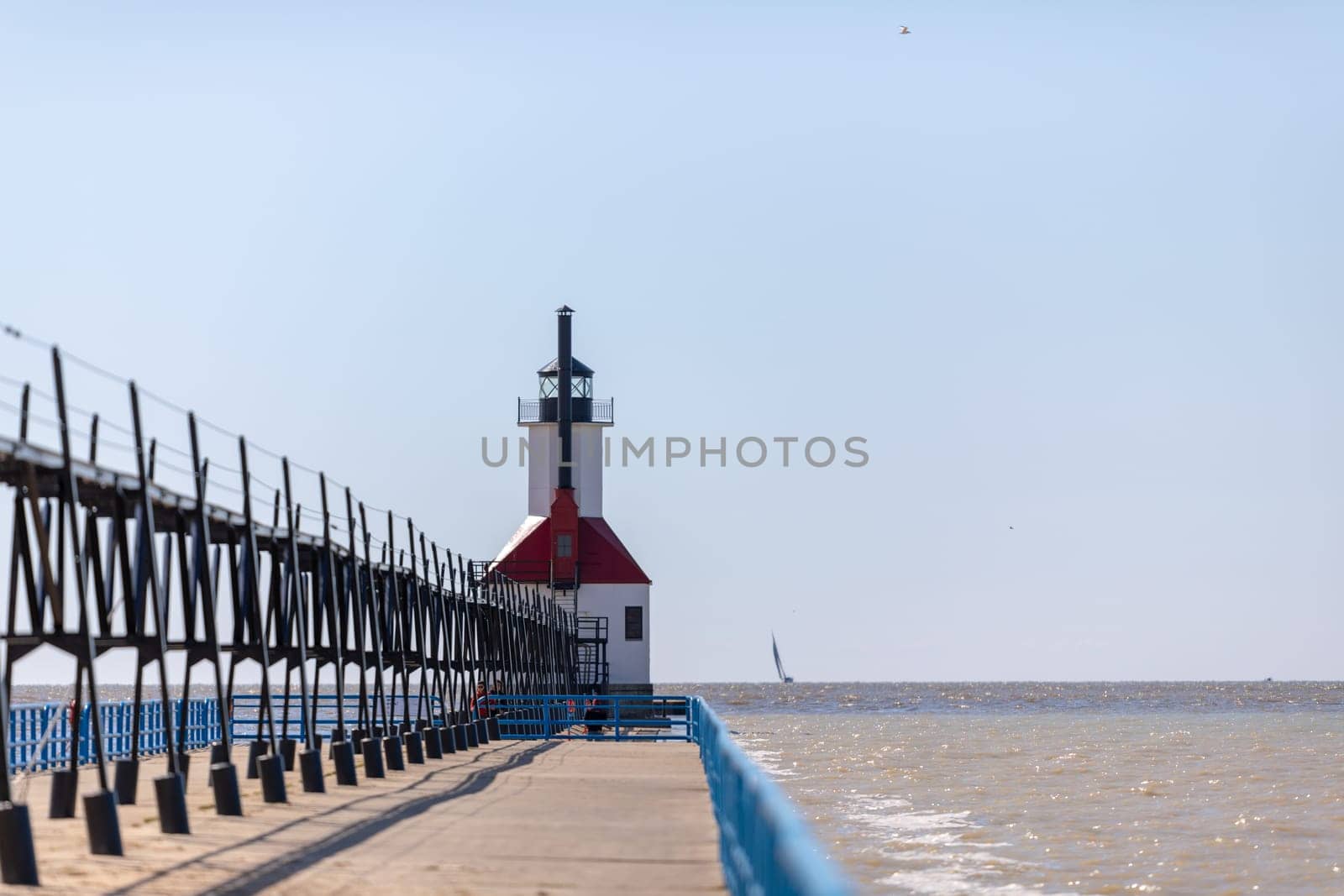St. Joseph, Michigan, USA - May 4, 2019: View from the north pier, with the lighthouse and a sail boat leaving the harbor