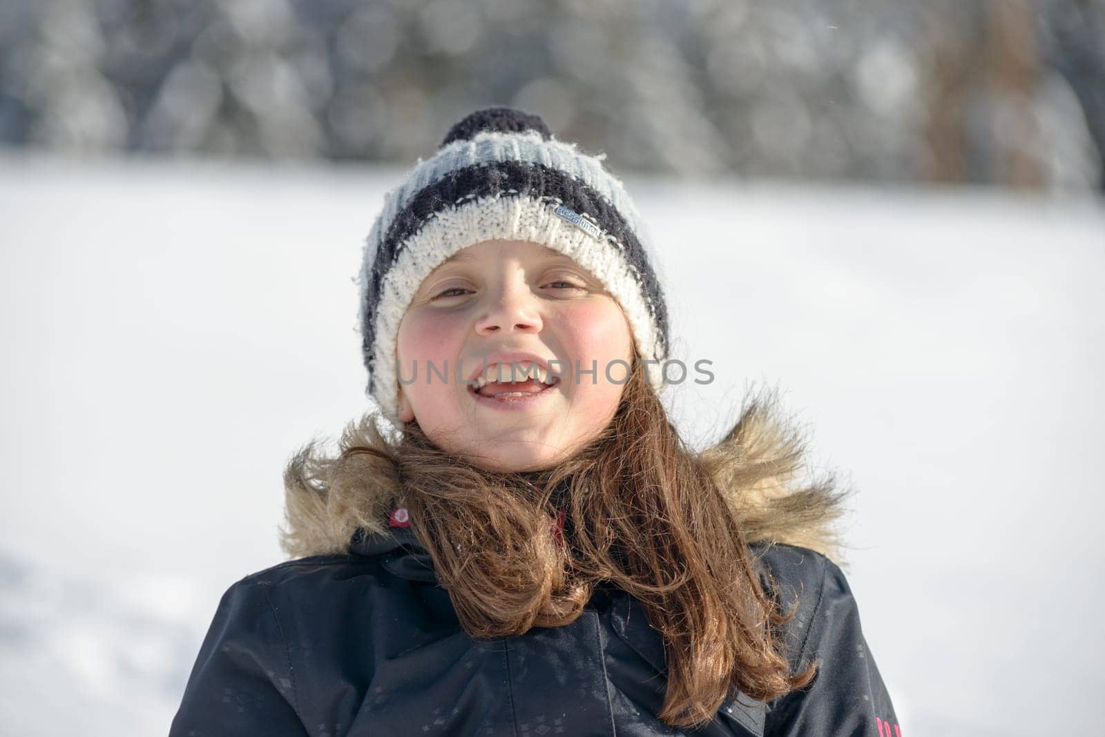 a smiling girl with a cap in the snow