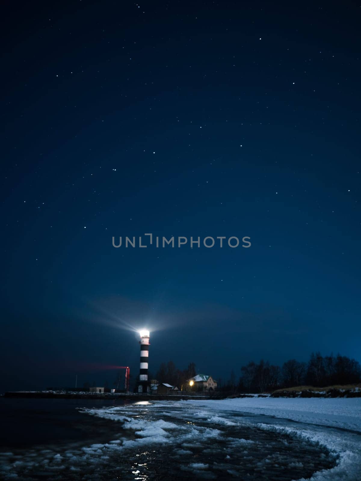 Riga Lighthouse in a starry night with frozen Baltic sea