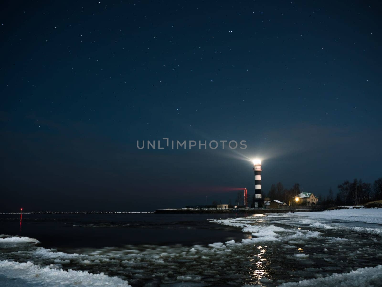 Riga Lighthouse in a starry night with frozen Baltic sea