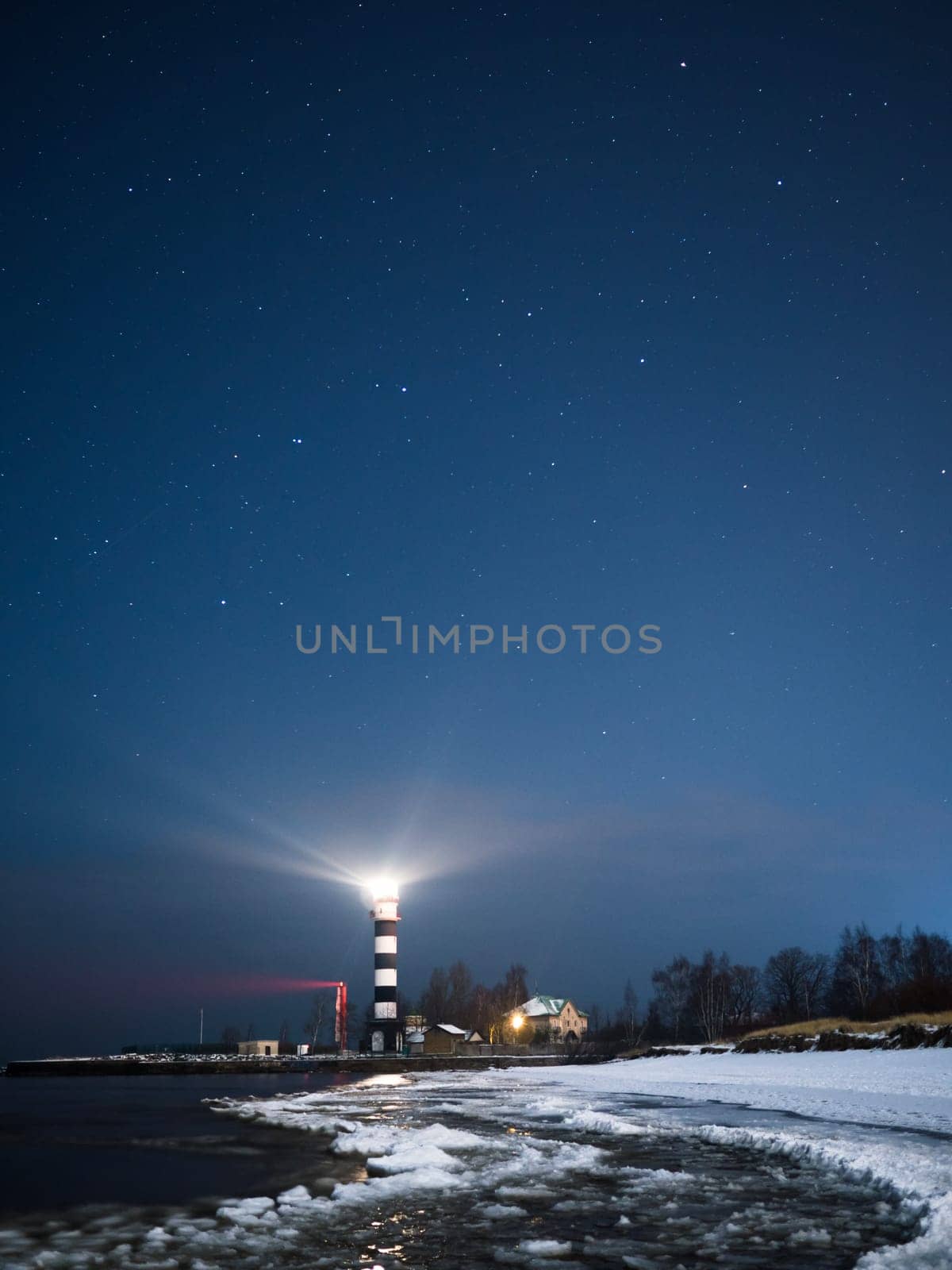 Riga Lighthouse in a starry night with frozen Baltic sea