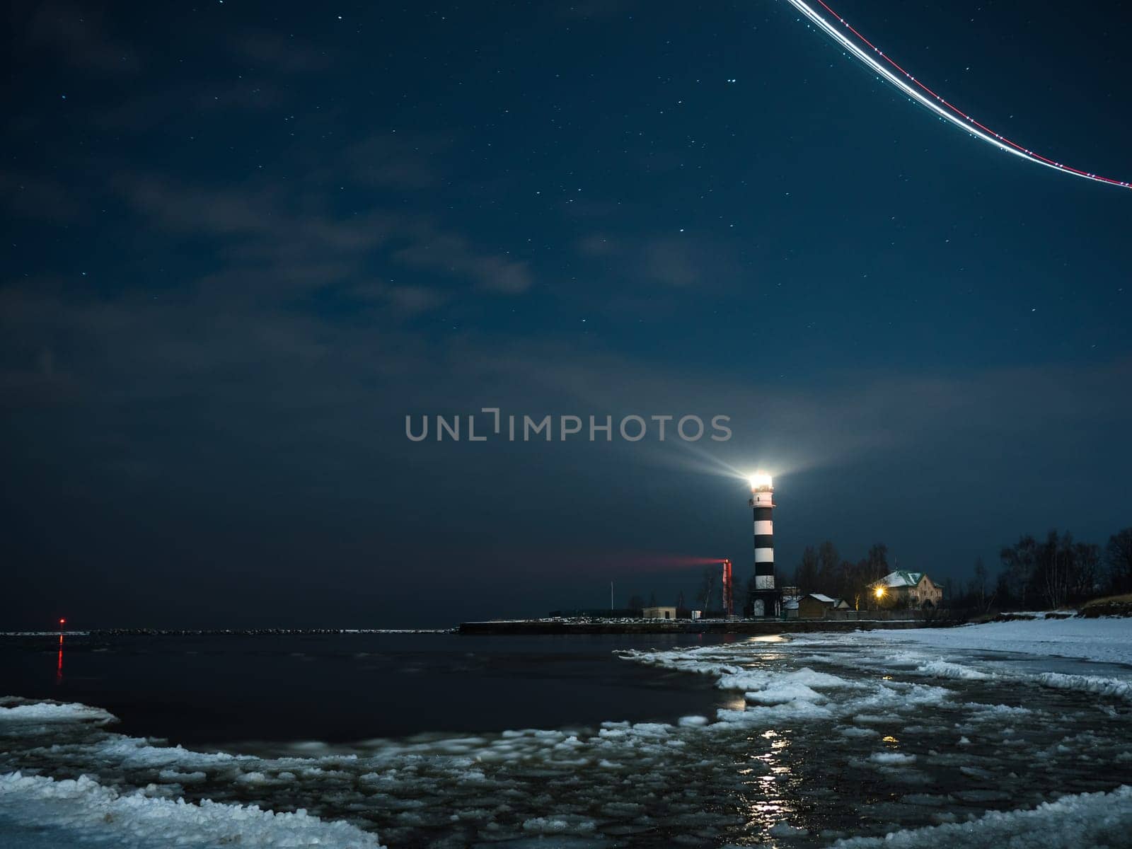 Riga Lighthouse in a starry night with frozen Baltic sea