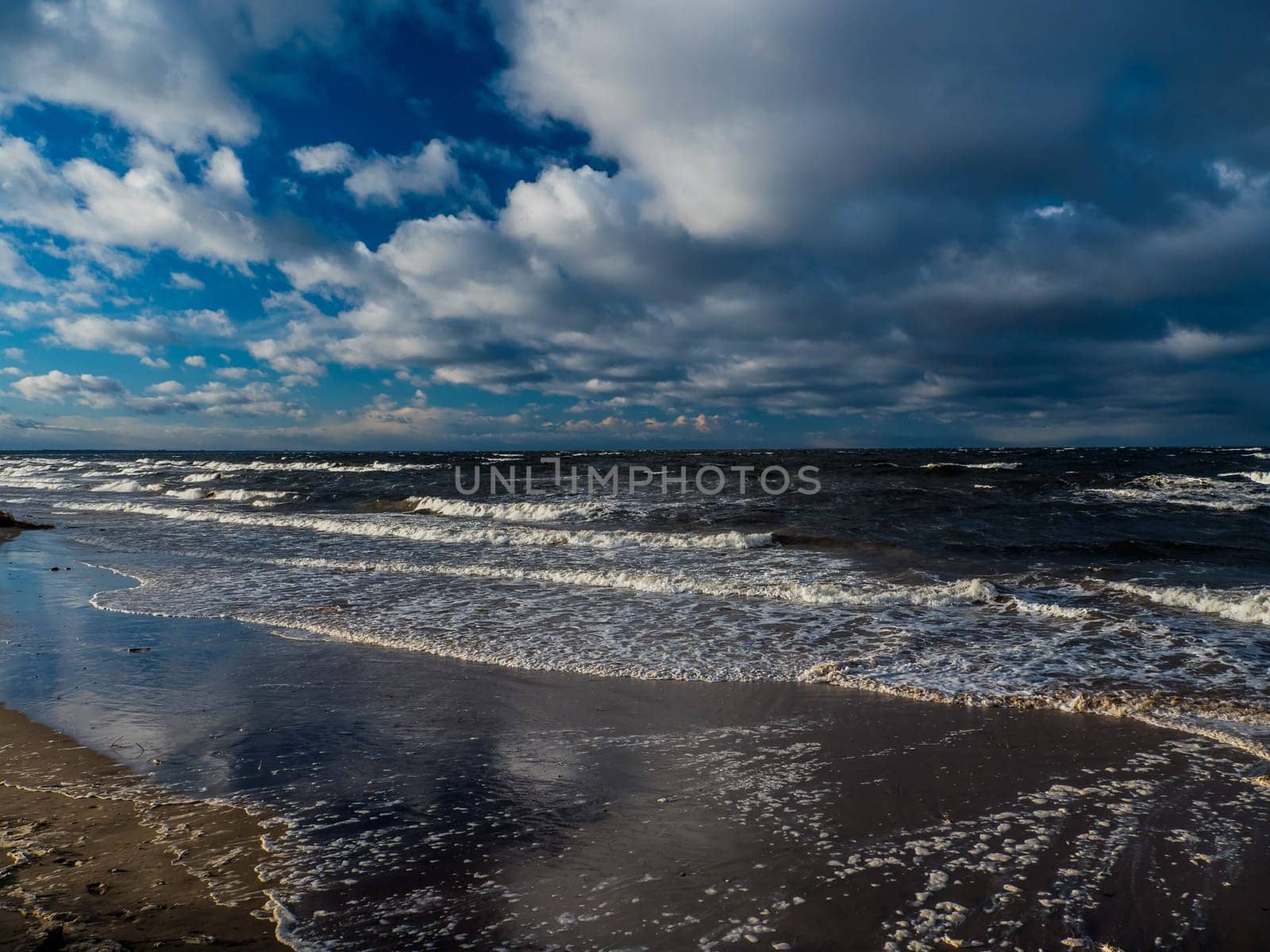 Baltic sea beach with blue cloudy sky and waves