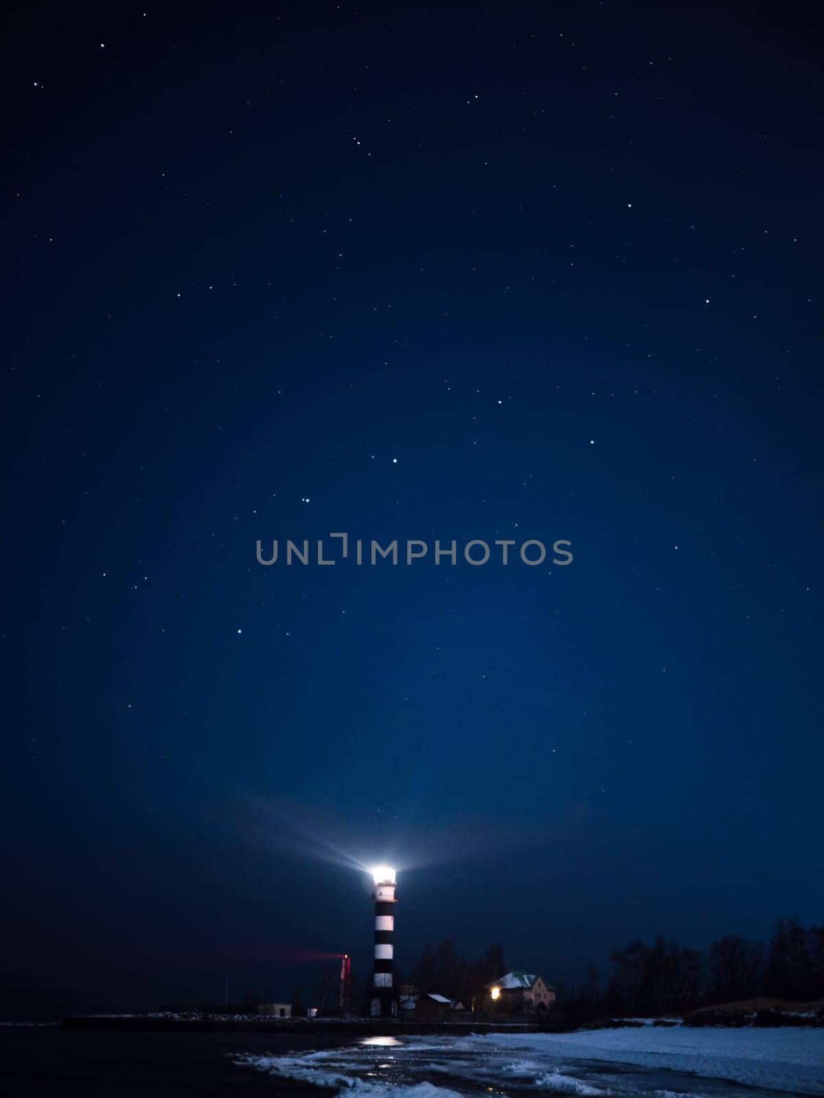 Riga Lighthouse in a starry night with frozen Baltic sea