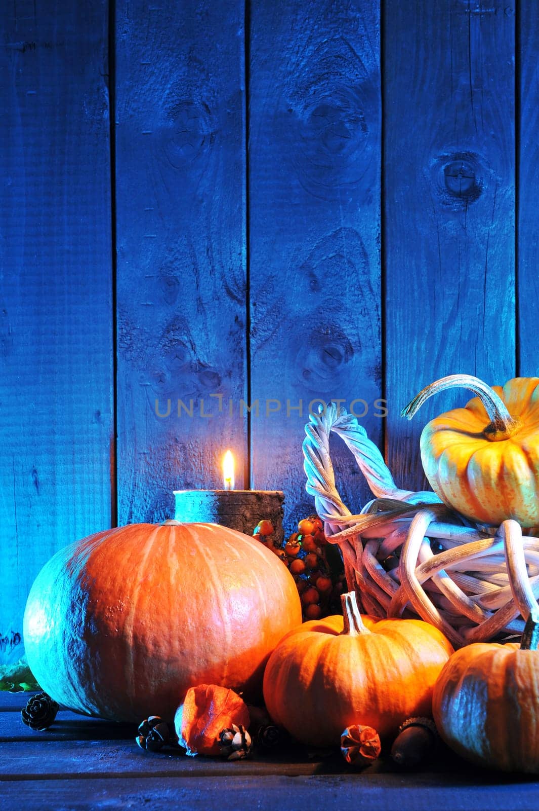 Halloween pumpkins in rattan basket in front of an old weathered wooden wall in blue light