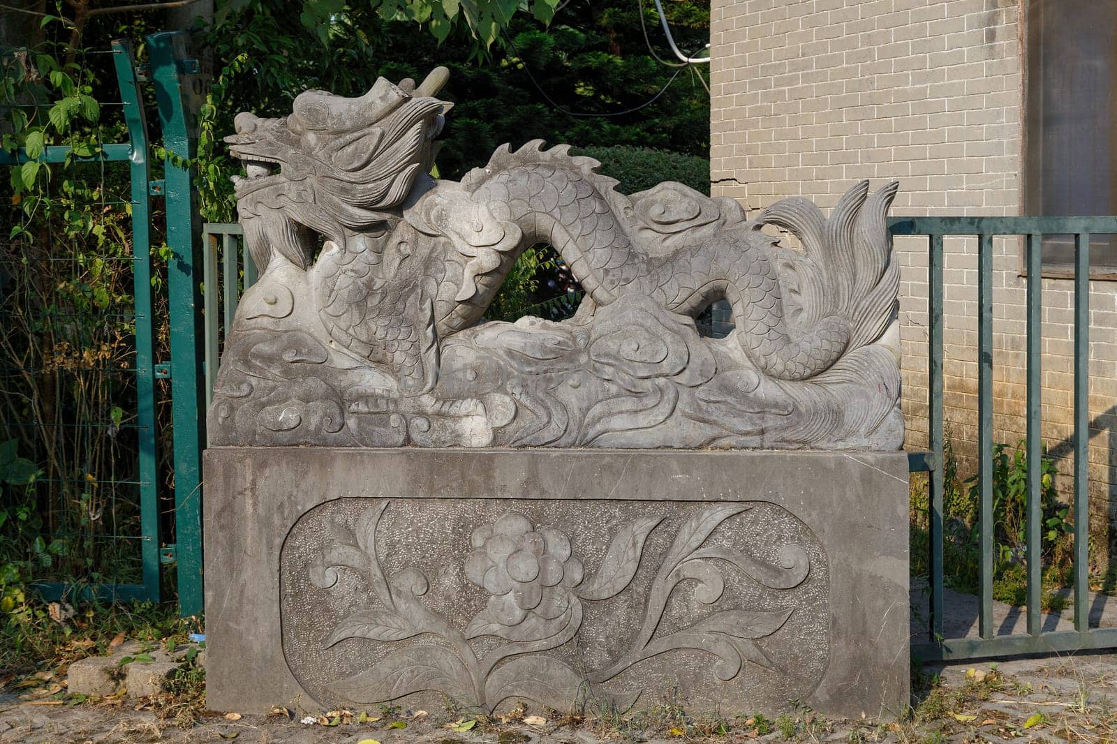 Figurine of a Chinese dragon made of concrete on a village street on a pedestal