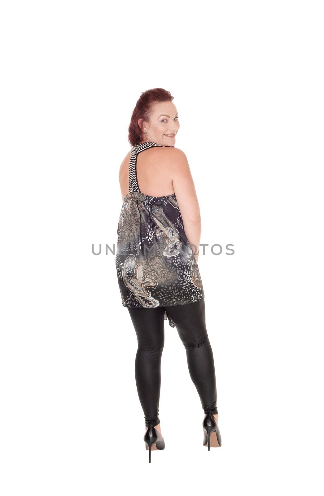 A gorgeous woman in black tights and a designer dress standing from.the back, looking over her shoulder, isolated for white background.