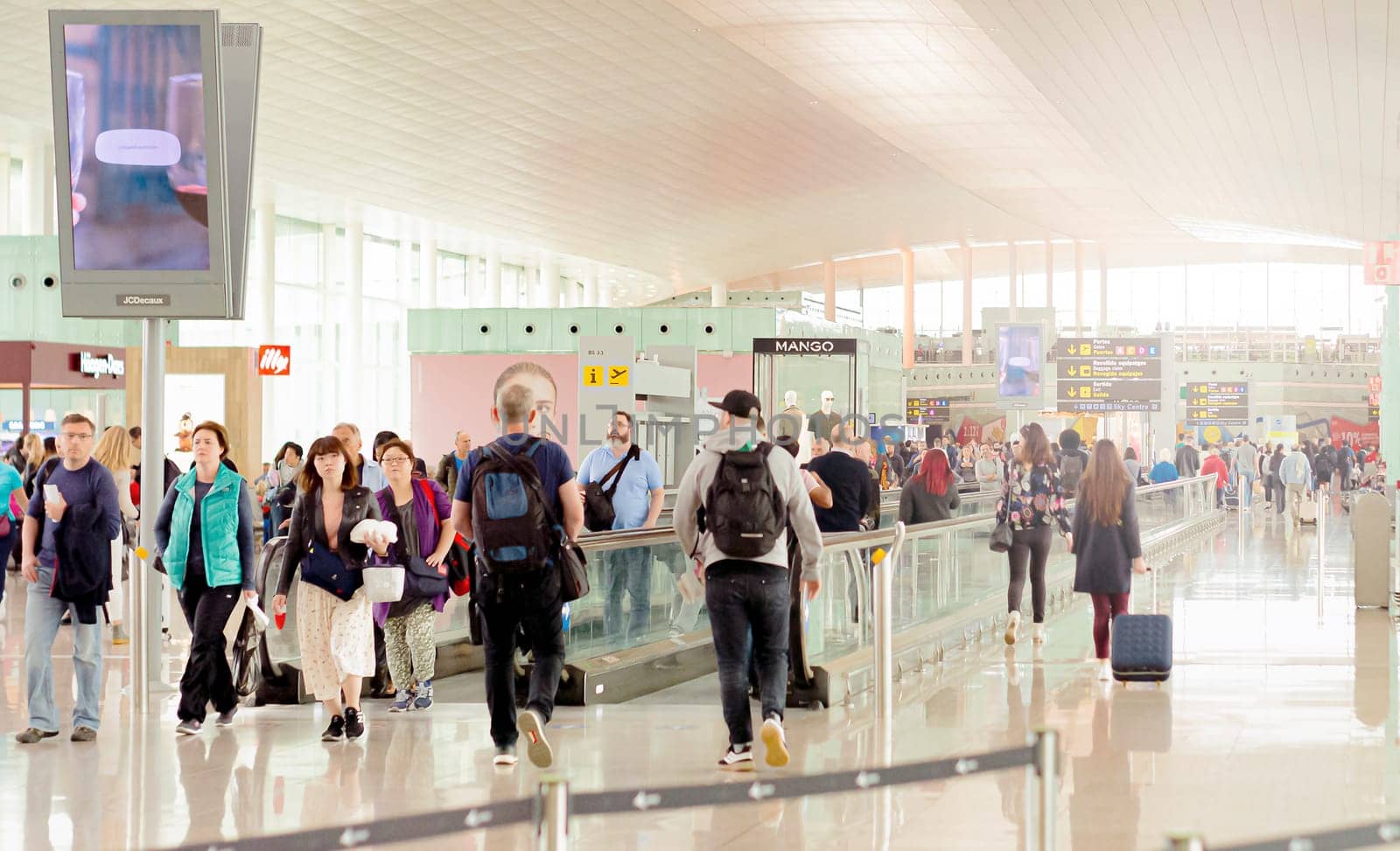 Barcelona, Spain, April 2019: people walking along the international departures corridor of El Prat airport in Barcelona, Spain