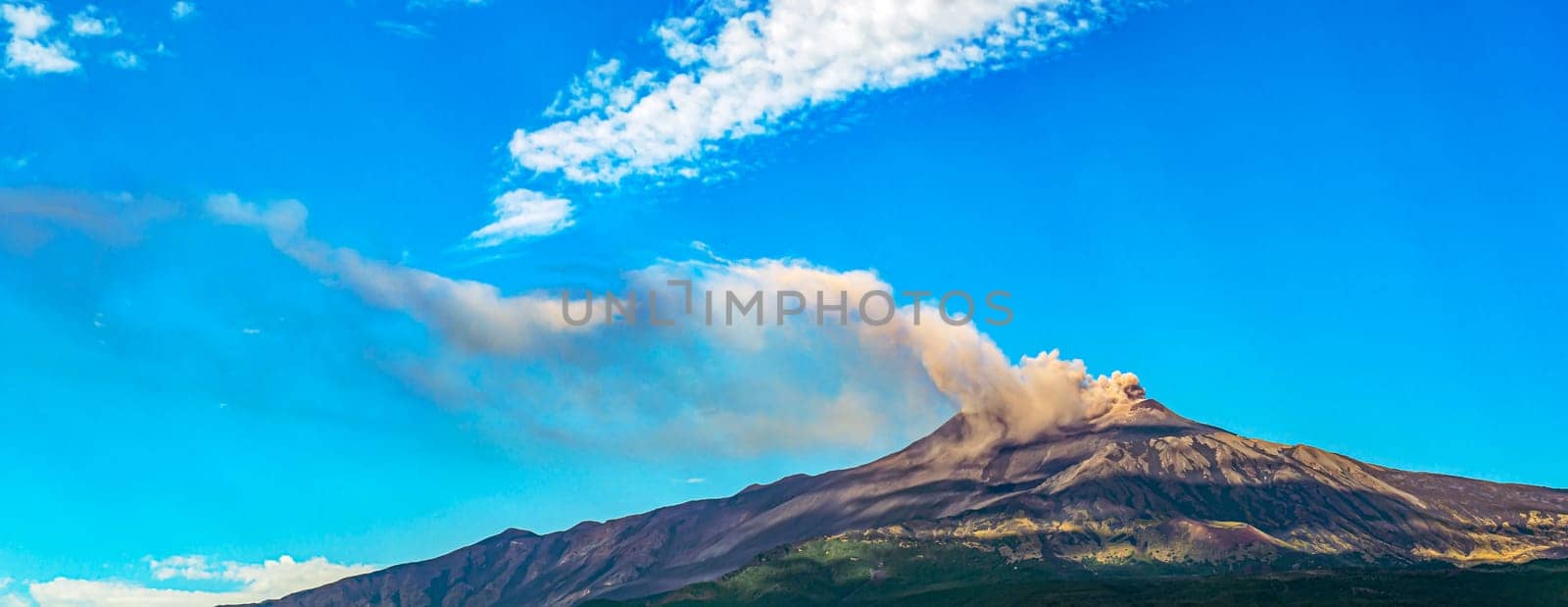 Overview of Mount Etna in Sicily during an eruption with smoke and ash release.