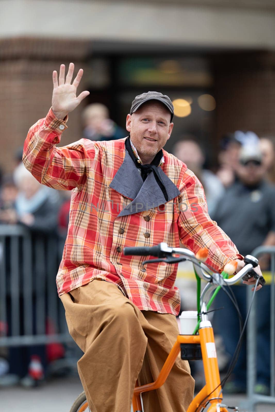 Holland, Michigan, USA - May 11, 2019: Tulip Time Parade, Man wearing traditional dutch clothing, smiling waving at people, going down the road during the parade on a bicycle