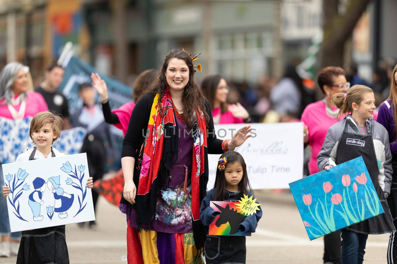 Holland, Michigan, USA - May 11, 2019: Tulip Time Parade, Woman accompanying children displaying their dutch related artworks during the parade