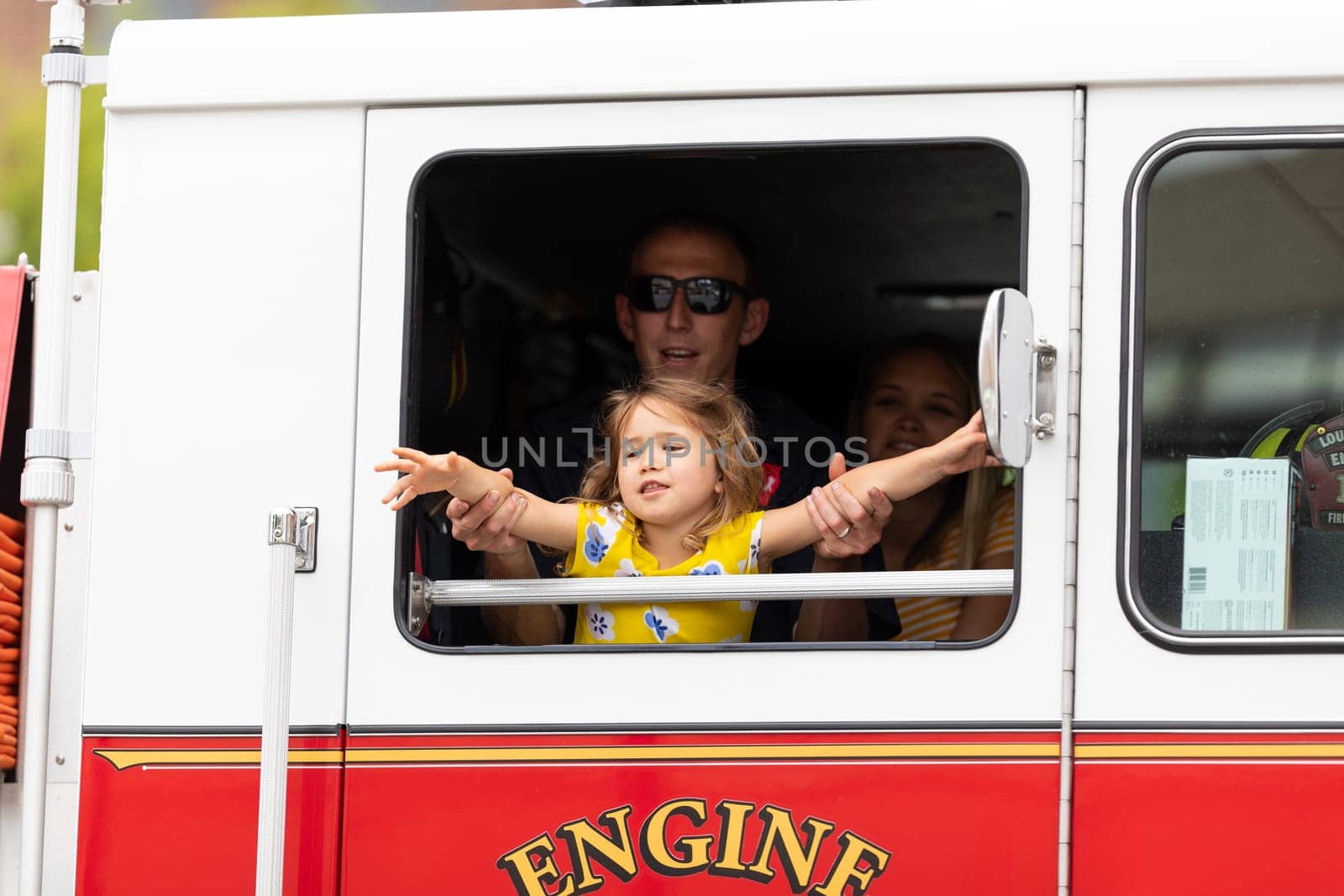 Louisville, Kentucky, USA - May 2, 2019: The Pegasus Parade, firefighter playing with his daugther inside a fire truck during the parade
