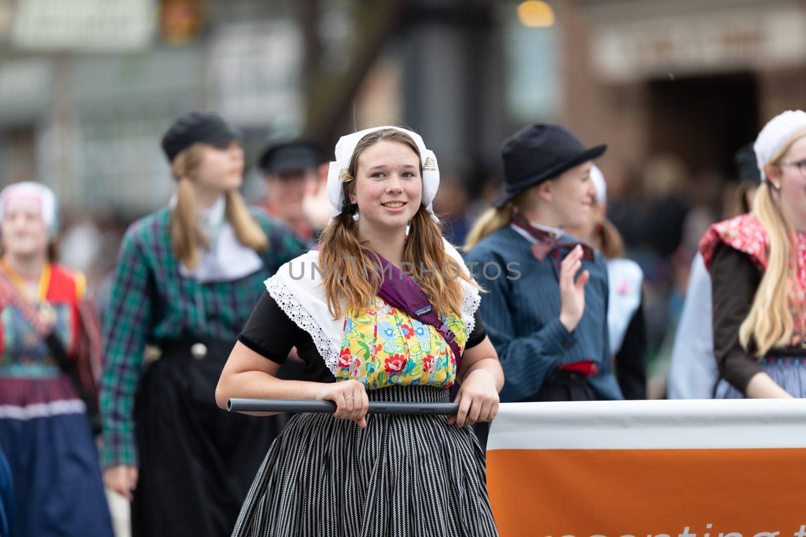 Holland, Michigan, USA - May 11, 2019: Tulip Time Parade, Young woman wearing traditional dutch clothing smiling, walking down the road during the parade
