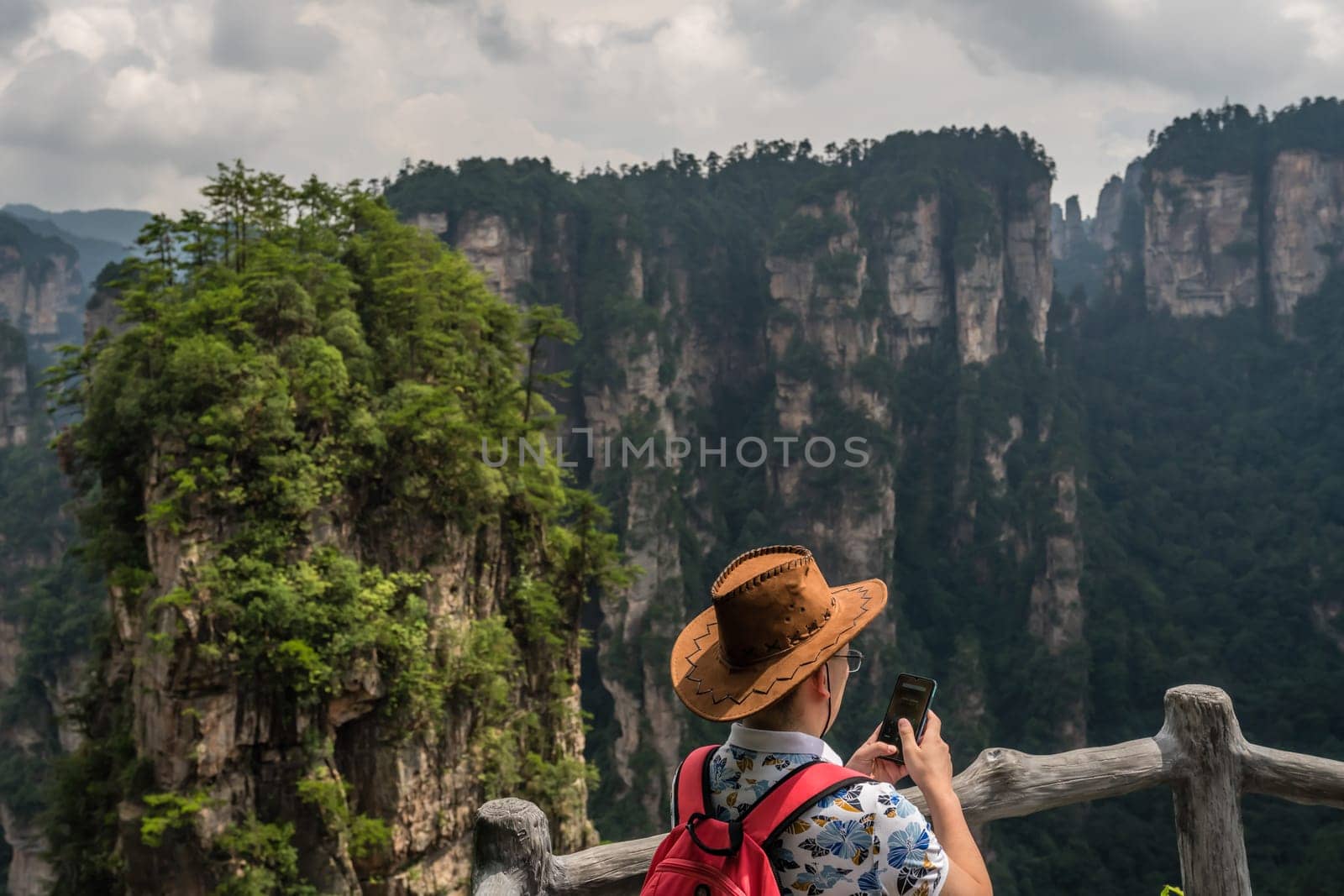 Zhangjiajie, China - August 2019 : Tourists admiring the view and taking pictures on the smartphone on the Bridge Heaven Pillar viewpoint, Avatar mountains nature park