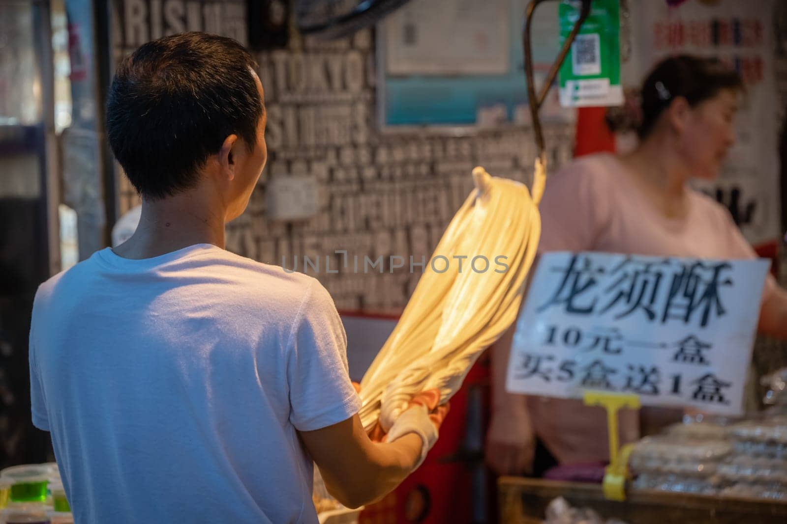 Xian, China -  July 2019 : Older man preparing dough for noodles and pasta in a traditional way on the street in the Muslim Quarter