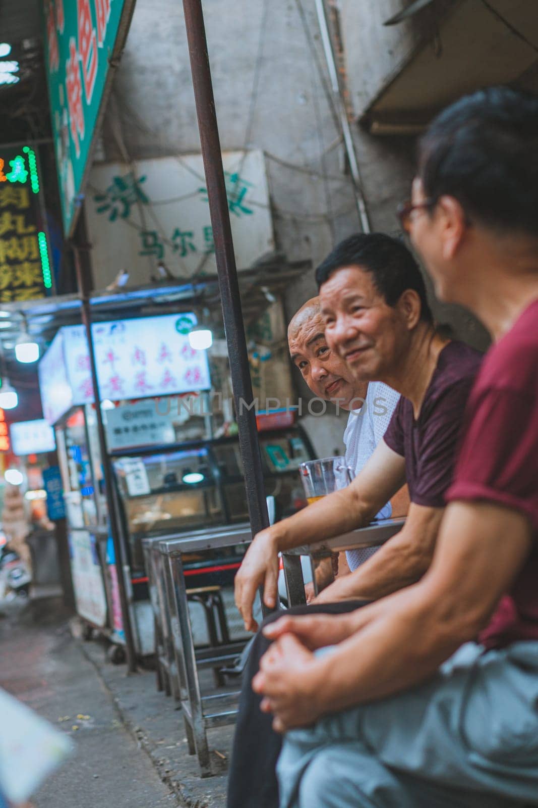 Xian, China -  July 2019 : Group of male friends talking and chatting behind a market stall in Muslim Quarter in Xian town, Shaanxi Province