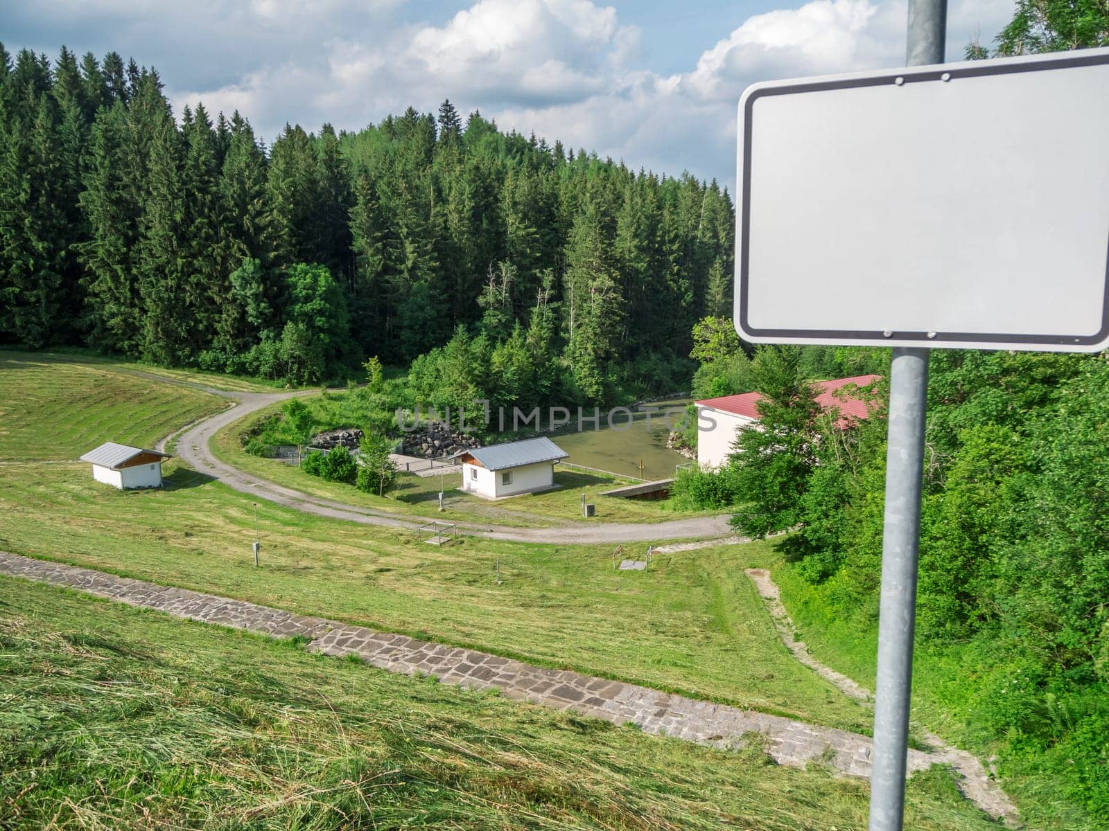 View from the dam on the power plant at the Lake Gruenten with empty sign in the foreground in summer 2019.