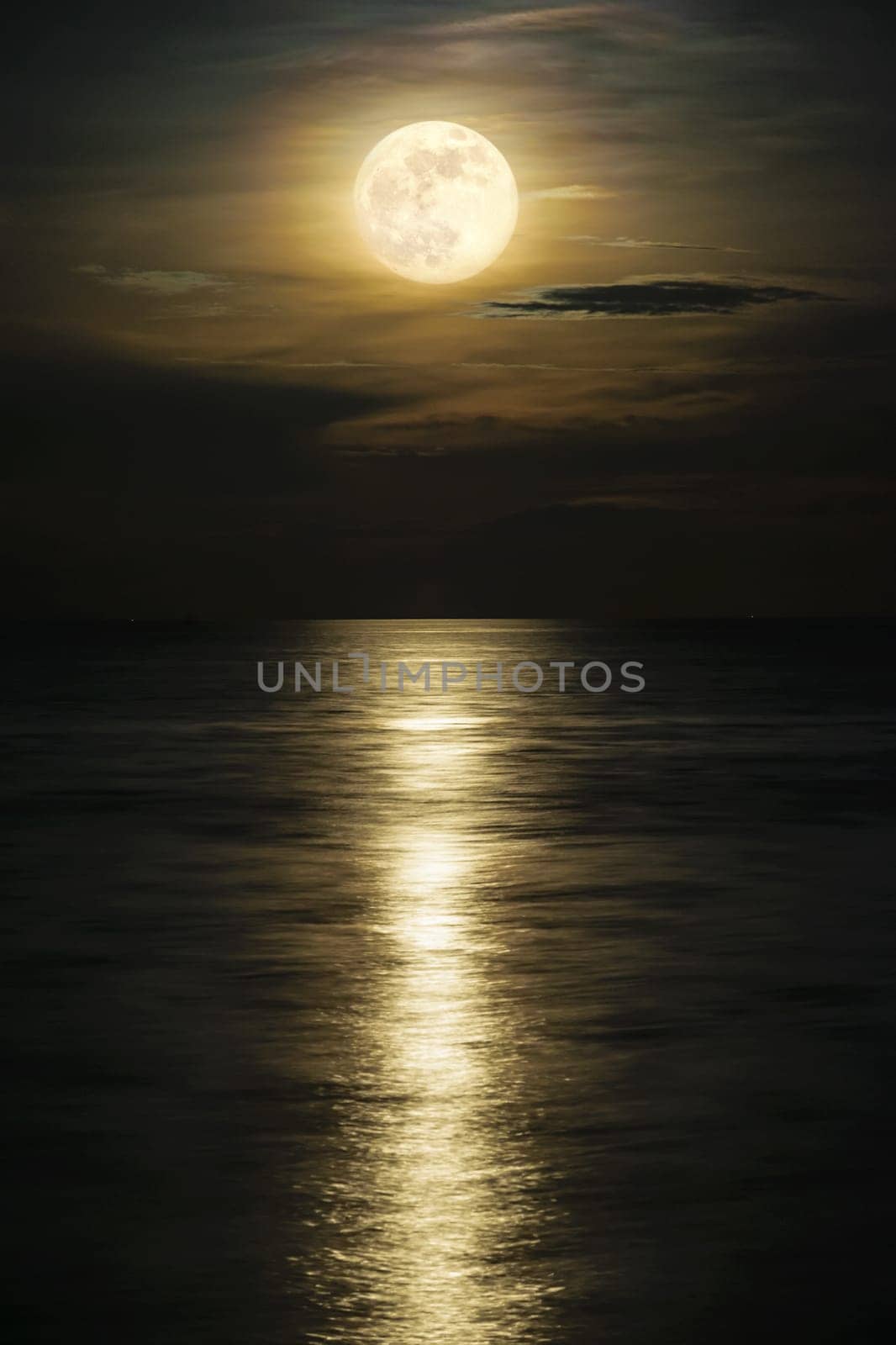 Super full moon and cloud in the yellow sky above the ocean horizon at midnight, moonlight reflect the water surface and wave, Beautiful nature landscape view at night scene of the sea for background