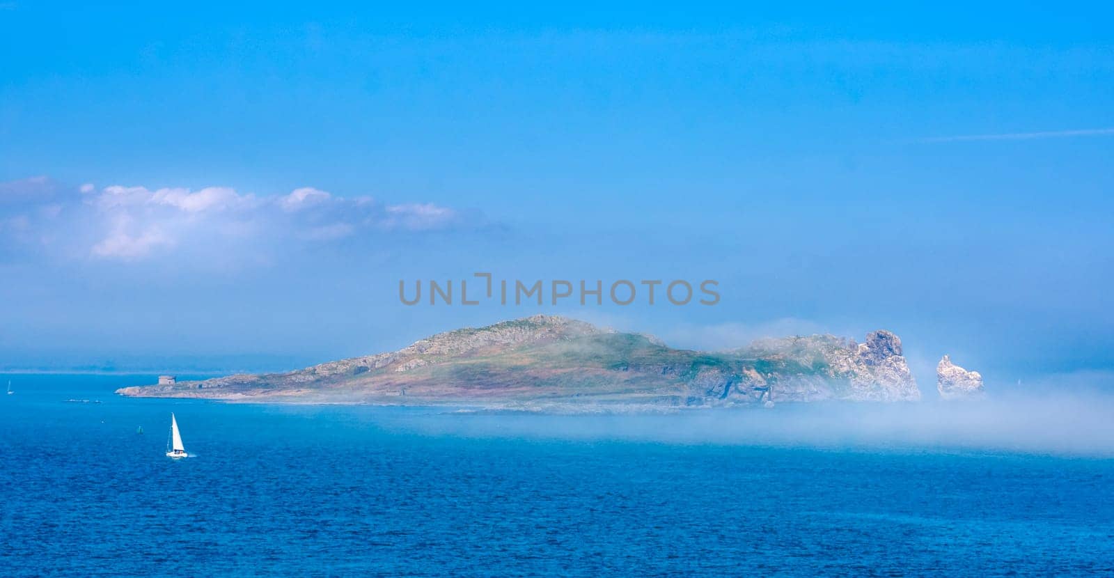Low lying fog or mist approaching and covering Irelands Eye island, unusual phenomenon, panoramic view from Howth, Dublin, Ireland