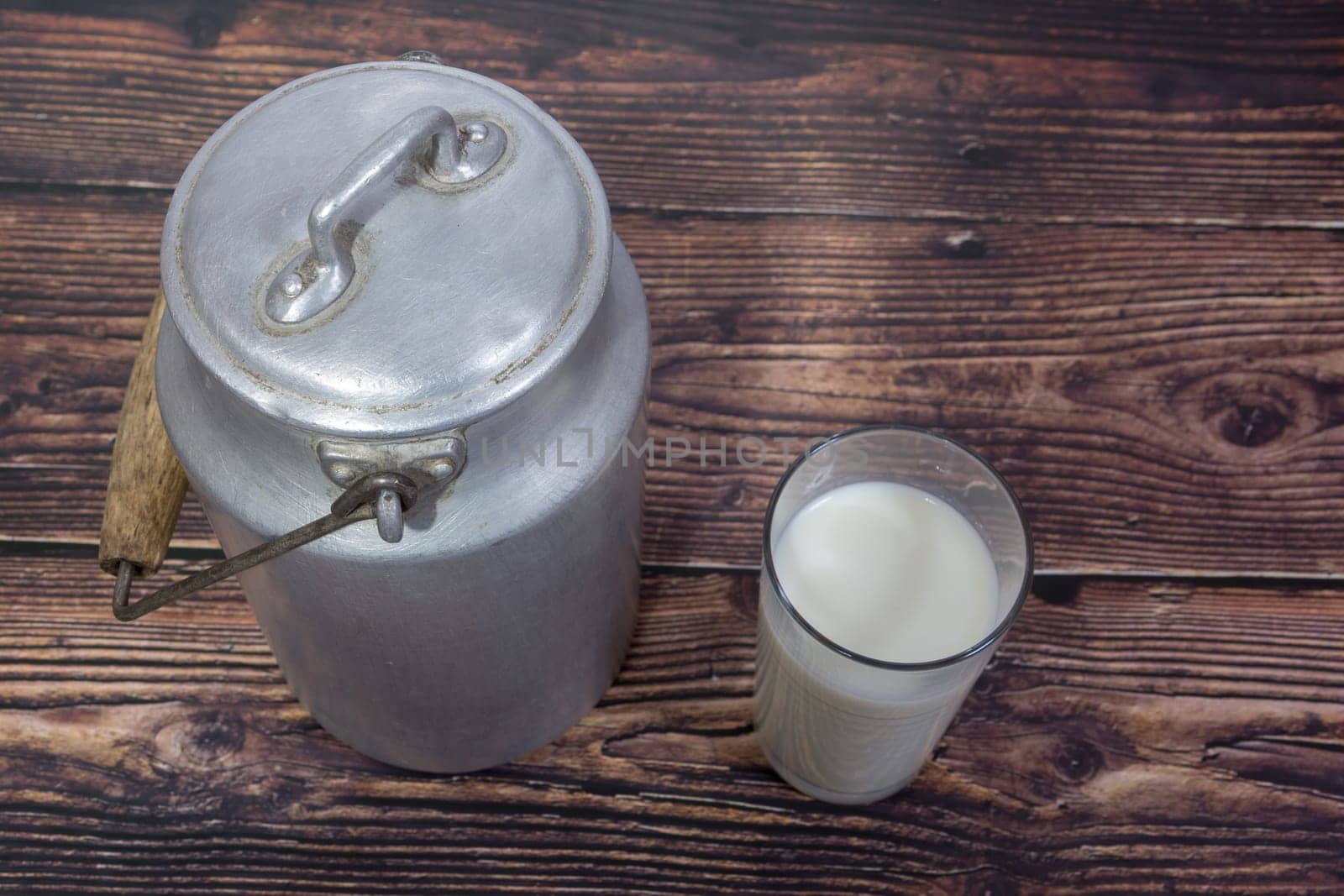 Can and glass of milk on brown wooden background