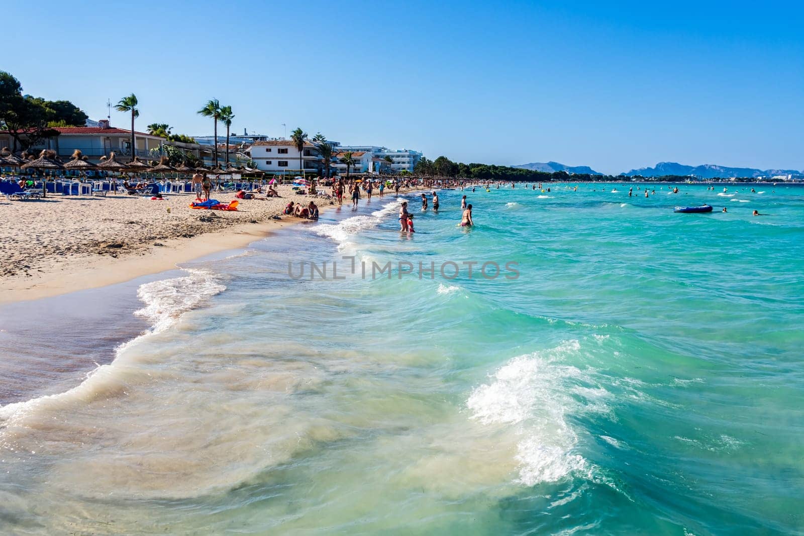 Mallorca, Spain, June 2015 People, tourists enjoying sun holidays on Alcudia beach, view on turquoise sea and sandy beach