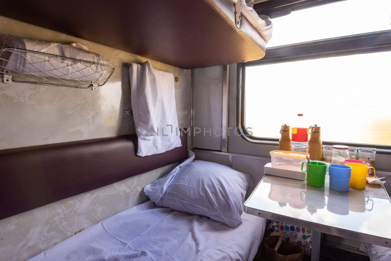 Empty bottom bunk in a reserved seat carriage and table with dishes