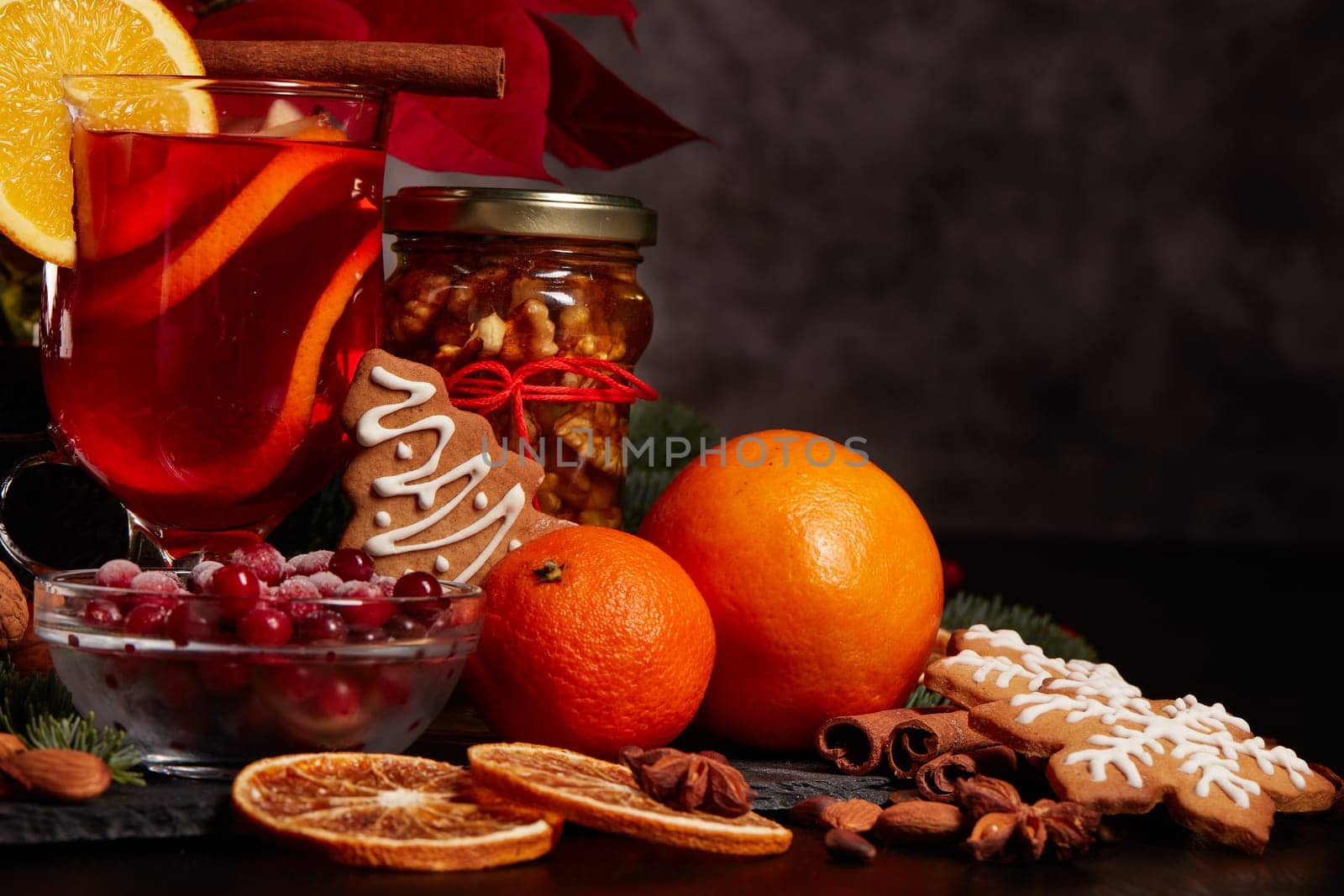 Still life with glasses of mulled wine or fruit tea, Red Poinsettia flowers, fir branch and spices on a dark background with copy space. New year and Christmas table setting. Greeting card.