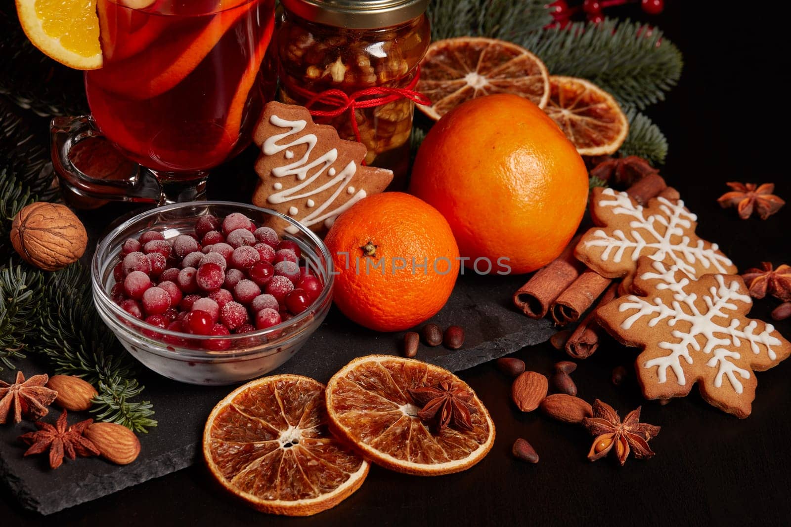 Still life with glasses of mulled wine or fruit tea, Red Poinsettia flowers, fir branch and spices on a dark background. New year and Christmas table setting. Greeting card.