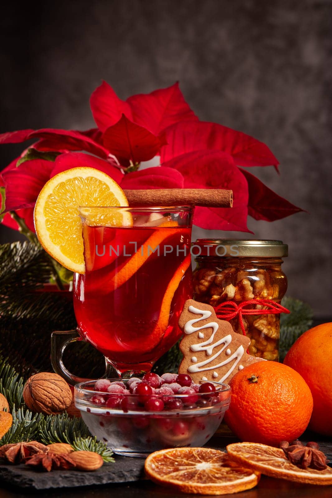 Still life with glasses of mulled wine or fruit tea, Red Poinsettia flowers, fir branch and spices on a dark background. New year and Christmas table setting. Greeting card.