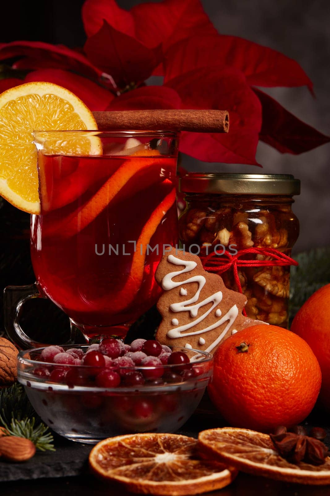 Still life with glasses of mulled wine or fruit tea, Red Poinsettia flowers, fir branch and spices on a dark background. New year and Christmas table setting. Greeting card.
