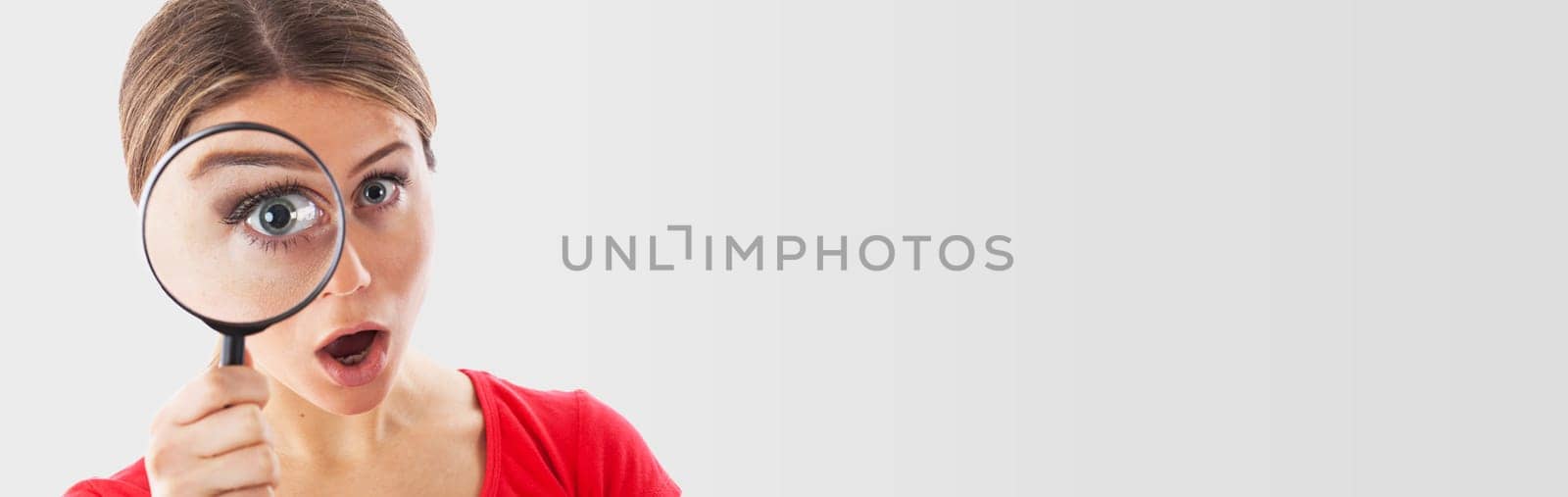 Girl looking through a magnifying glass and being surprised, isolated on white