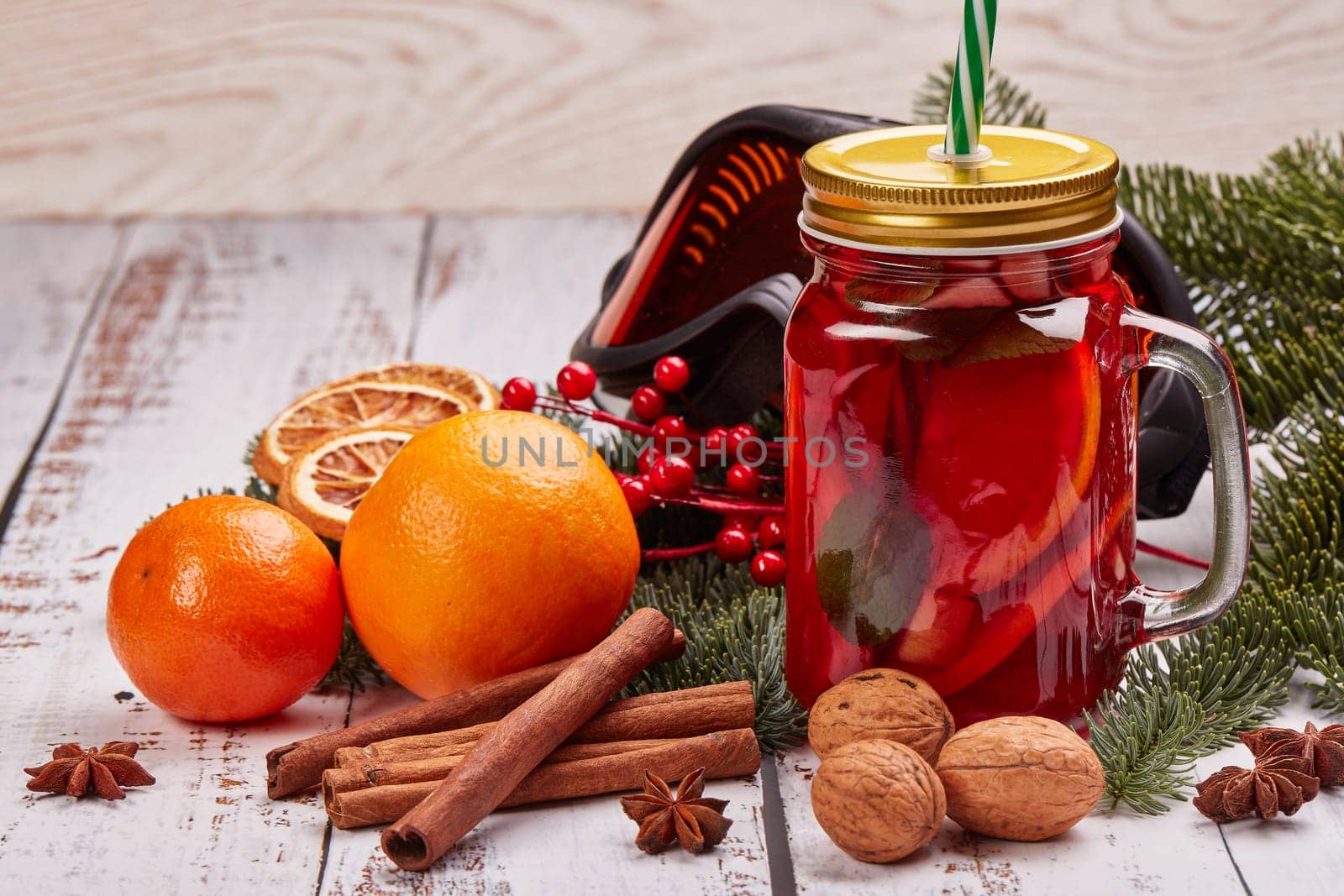 Winter holidays still life with fir tree branch, ski glasses, fruit tea, spices and oranges on a light wooden background with copy space. New Year and Christmas. Winter vacation.