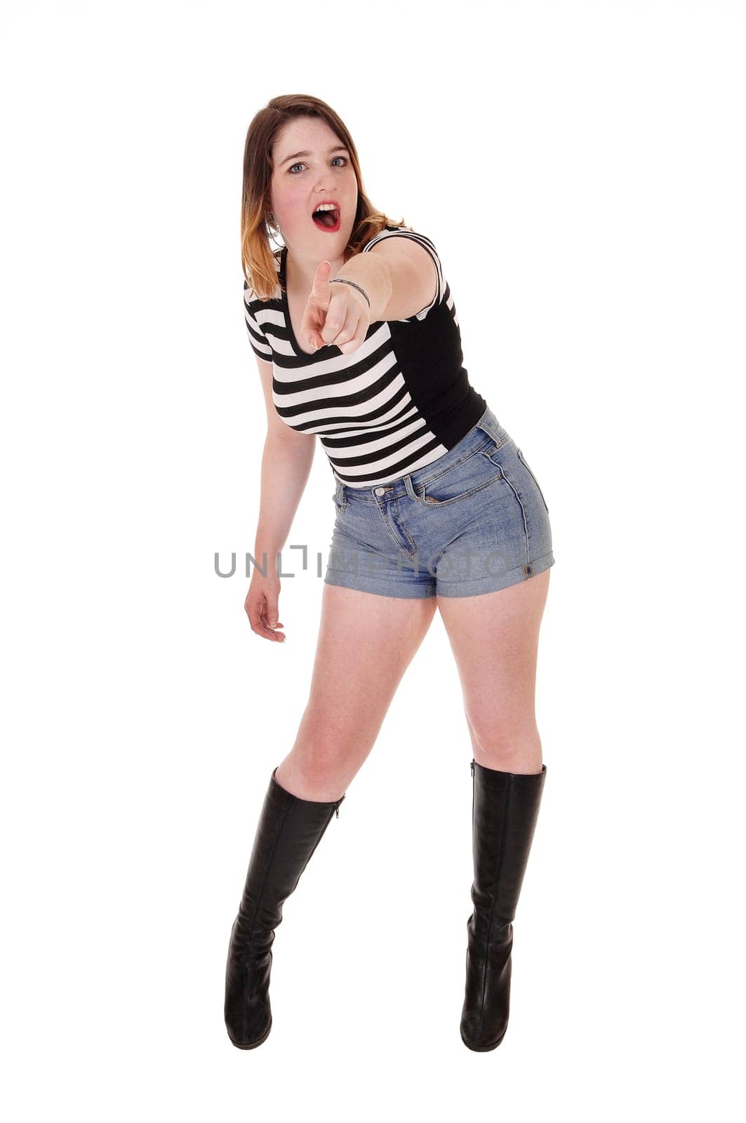 A pretty woman standing in shorts and black boots, pointing with her.finger and shouting, isolated for white background.
