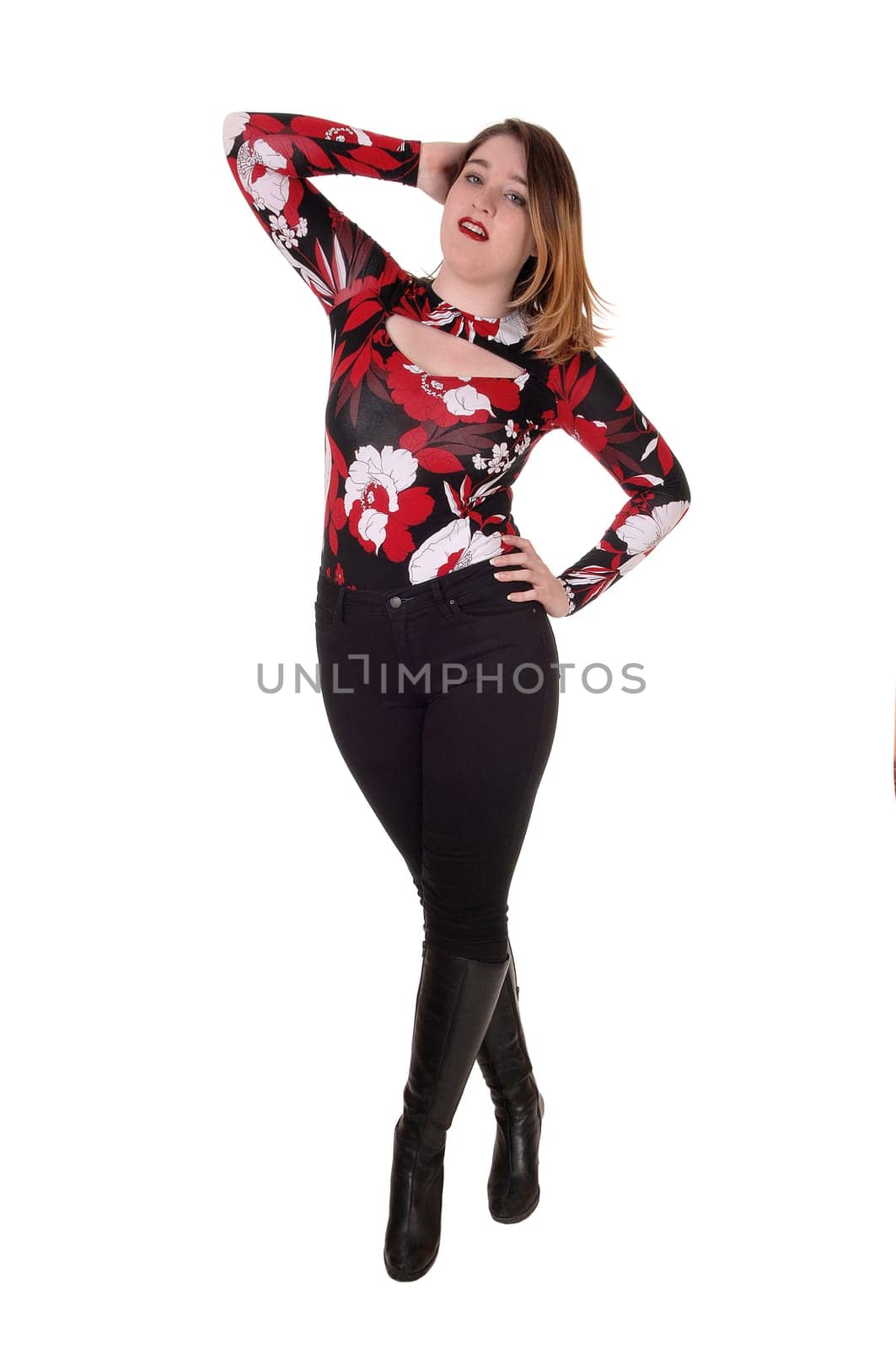 A gorgeous young woman standing isolated for white background with.one hand on her head in black tights and boots.