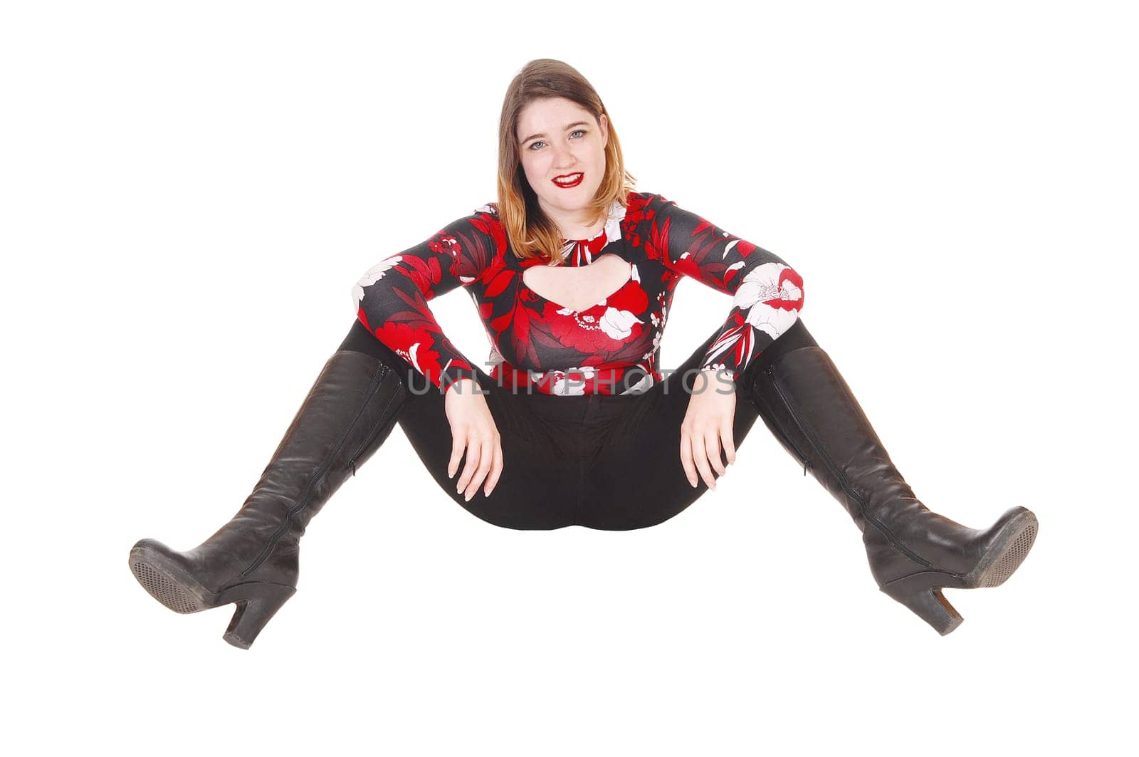 A beautiful young woman in a colorful blouse and black tights and.boots sitting on the floor, resting, isolated for white background.