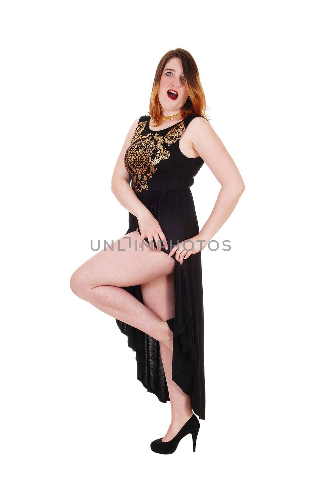 Beautiful young woman standing in a long black evening dress.showing her nice leg, isolated for white background.