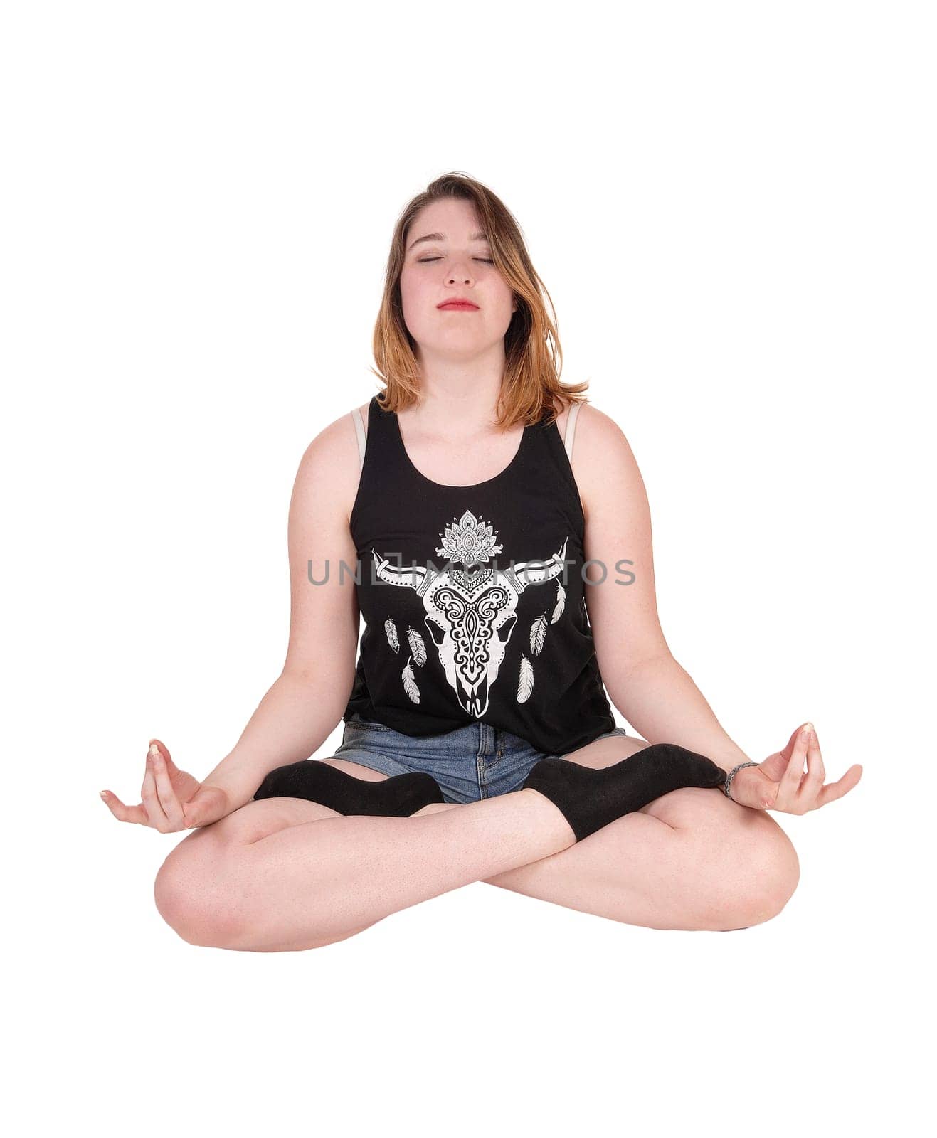 A beautiful blond woman sitting on the floor in a yoga pose with her.eyes closed, isolated for white background.