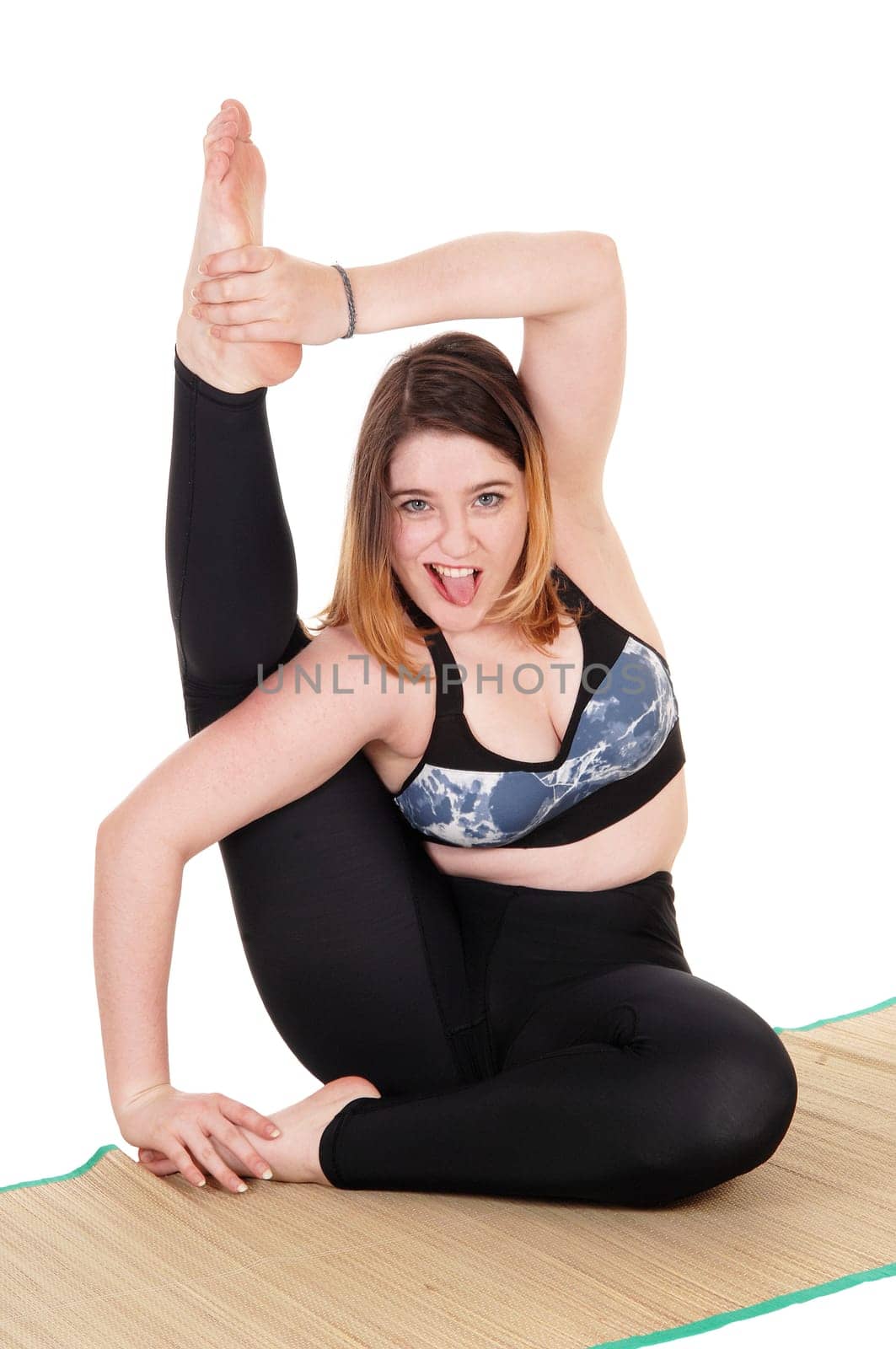 A beautiful young woman exercising on the floor with one leg behind.her head, in a sports outfit, isolated for white background.