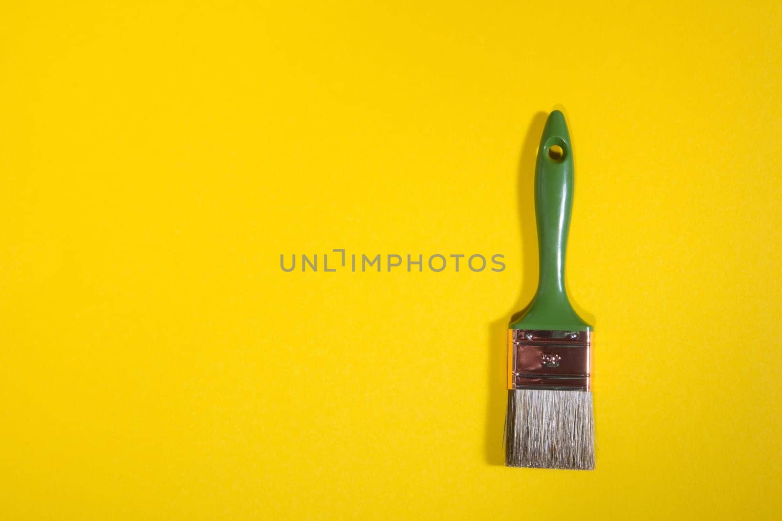 Green Paint brush on yellow background with copy space