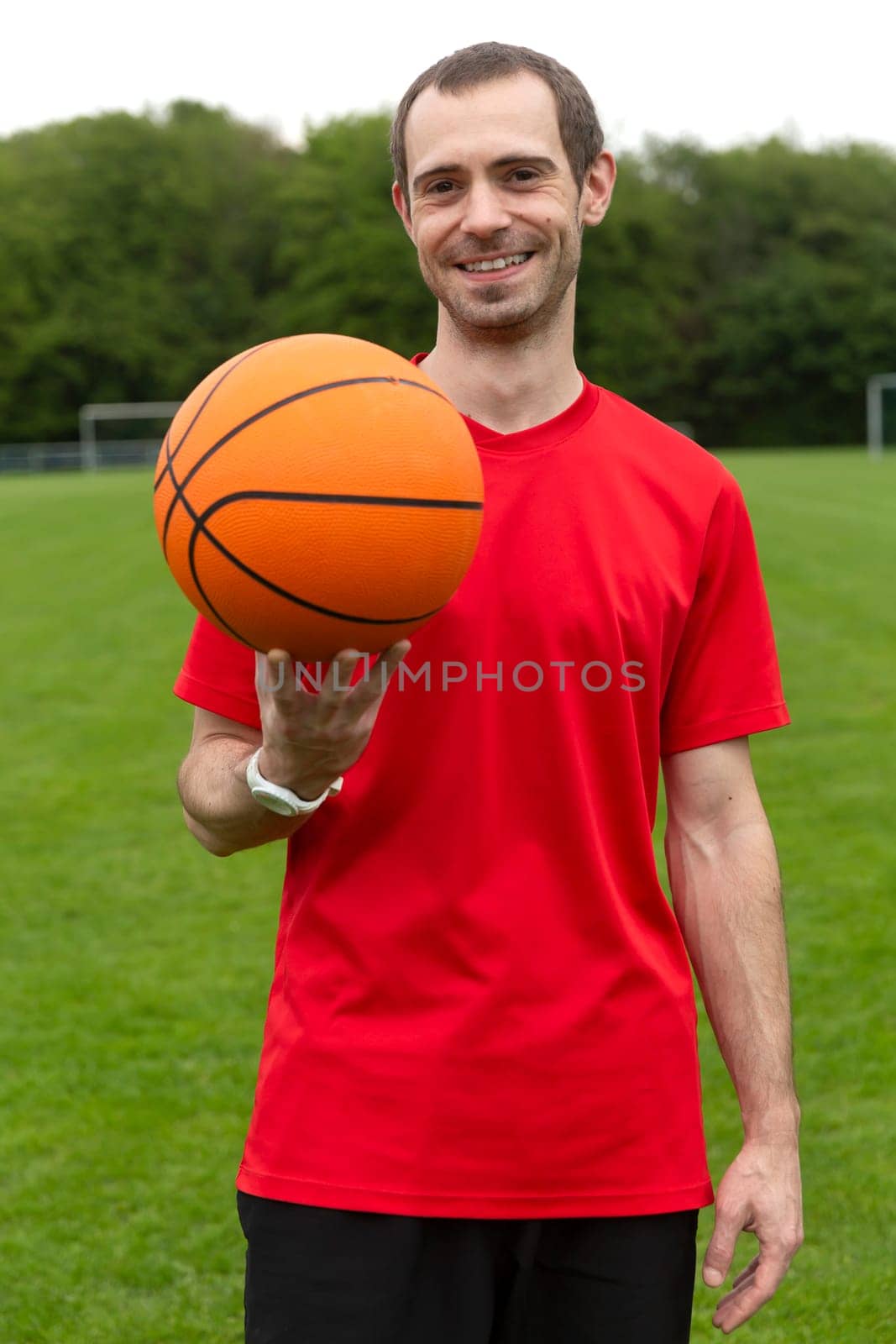 Young friendly man with basketball in soutdoor sports area
