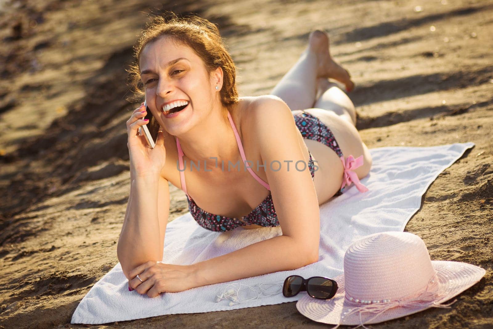 The cheerful laughing woman is talking on the phone and enjoying in summer.