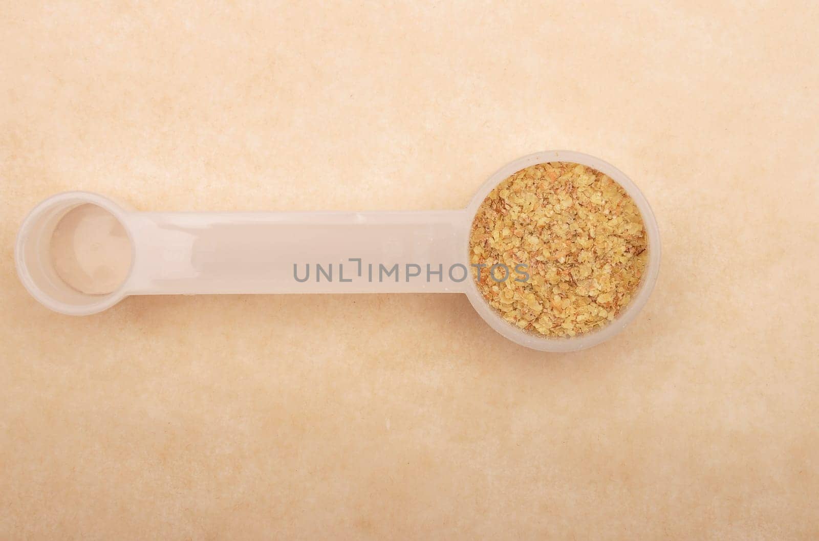 Wheat germs in measuring spoon on brown background